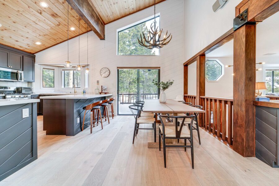Modern kitchen and dining area with antler chandelier in a Truckee vacation rental, featuring wood accents and forest views.