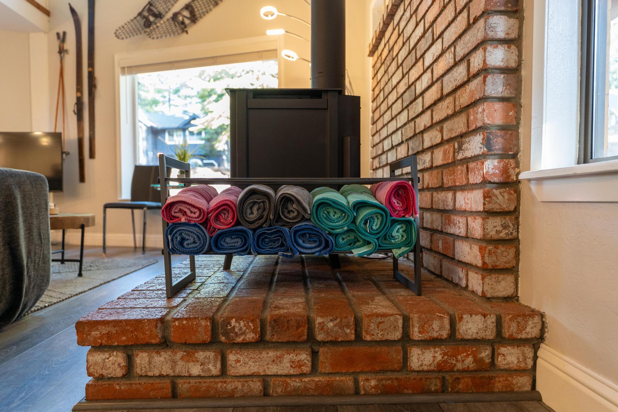 Cozy Tahoe Vista vacation rental with colorful towels on a rack, brick fireplace, and rustic decor, creating a welcoming ambiance.
