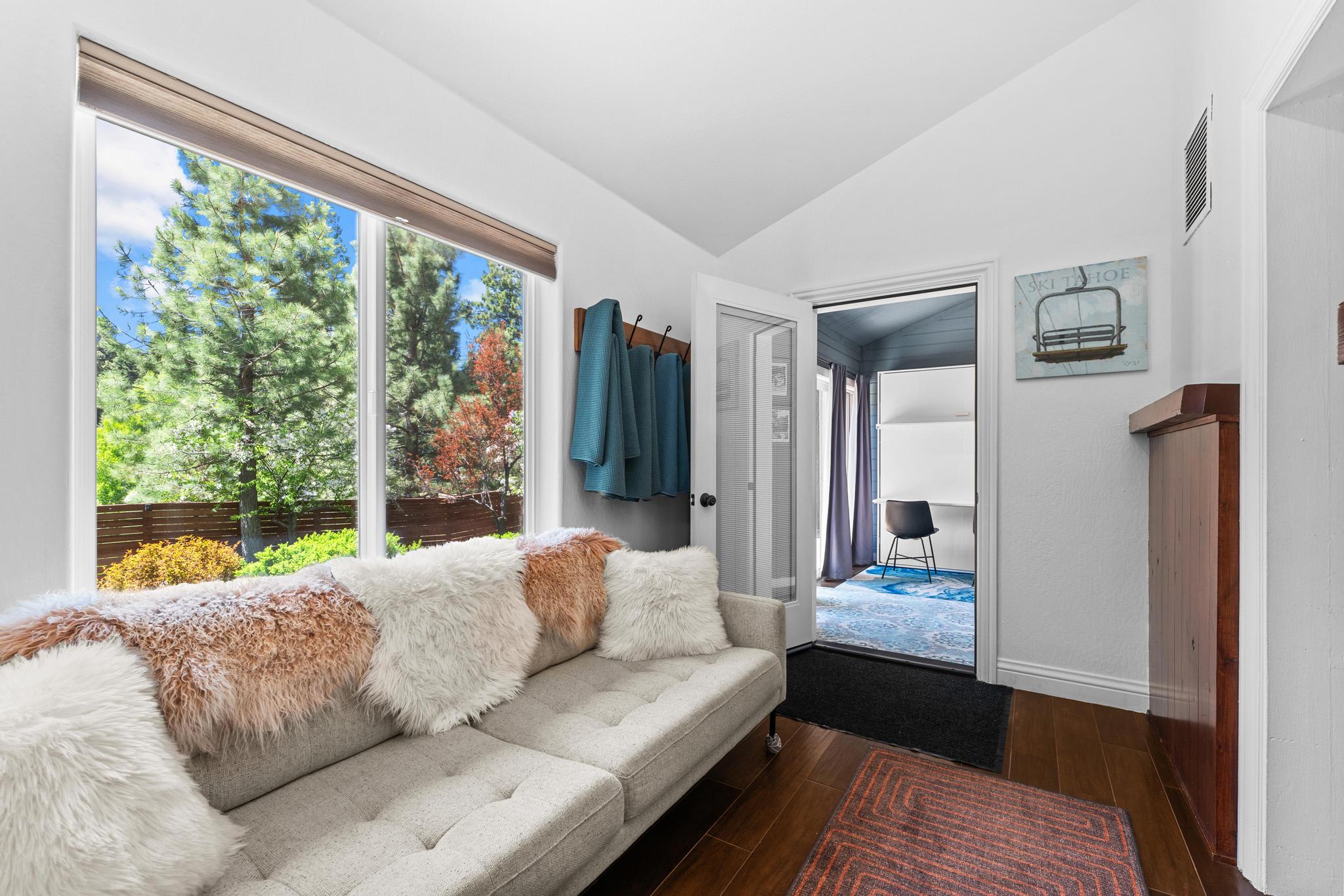 Bright interior of a Truckee vacation rental with plush sofa, windows to greenery, and cozy decor.