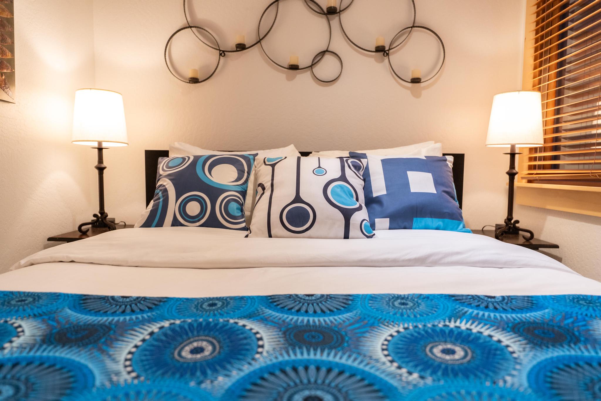 Cozy bedroom in a Truckee vacation rental with modern decor, blue patterned pillows, and warm lighting.