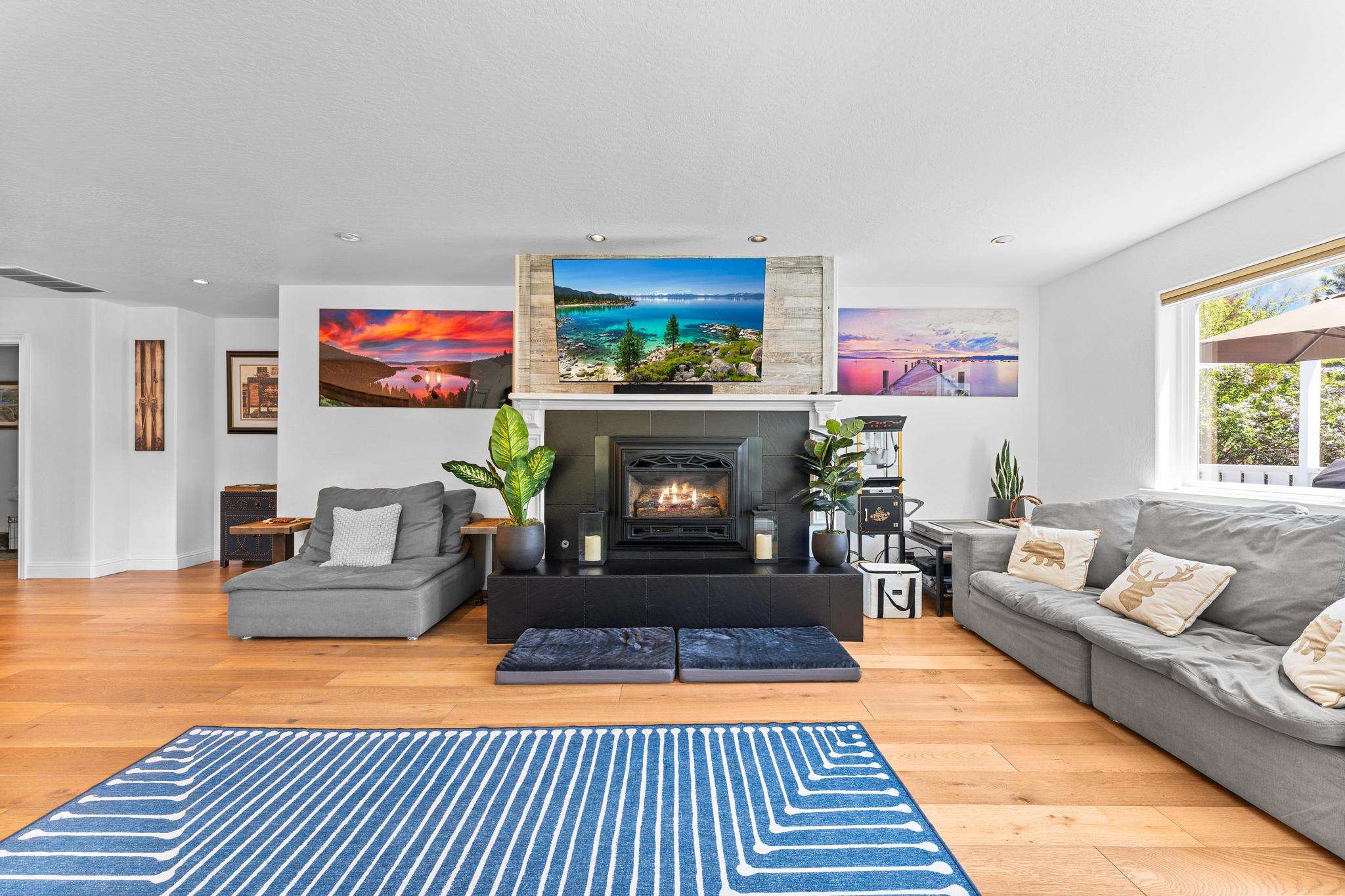 Spacious living room in a Truckee vacation rental, featuring a cozy fireplace, modern decor, and vibrant landscape art.