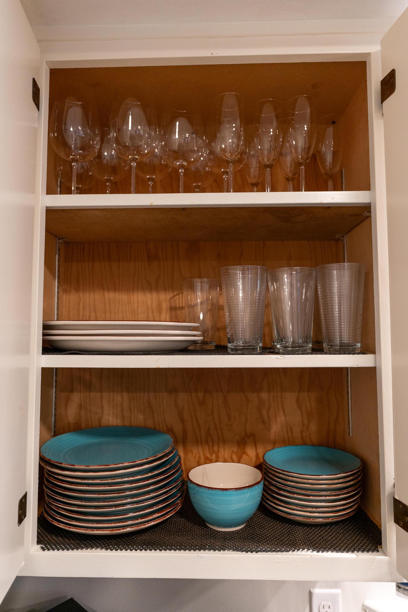 Shelves in a Tahoe Vista vacation rental displaying wine glasses, plates, and bowls neatly arranged in a cabinet.