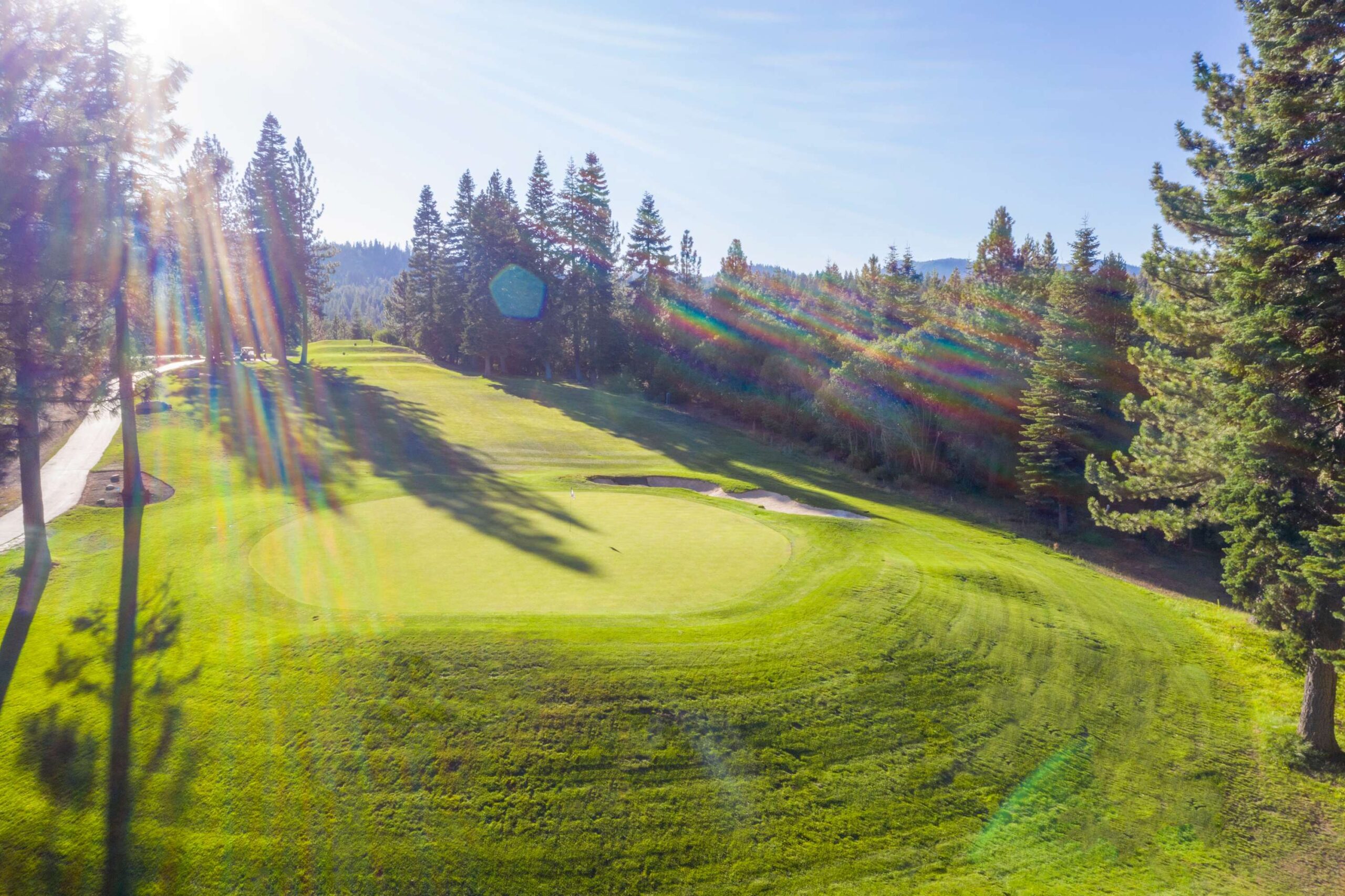 Sunlit golf course near a forest in Truckee, ideal for a vacation rental getaway.