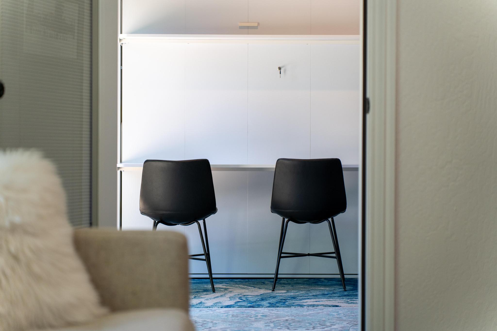 Modern Truckee vacation rental with two black chairs at a minimalist desk, viewed from a cozy living area.