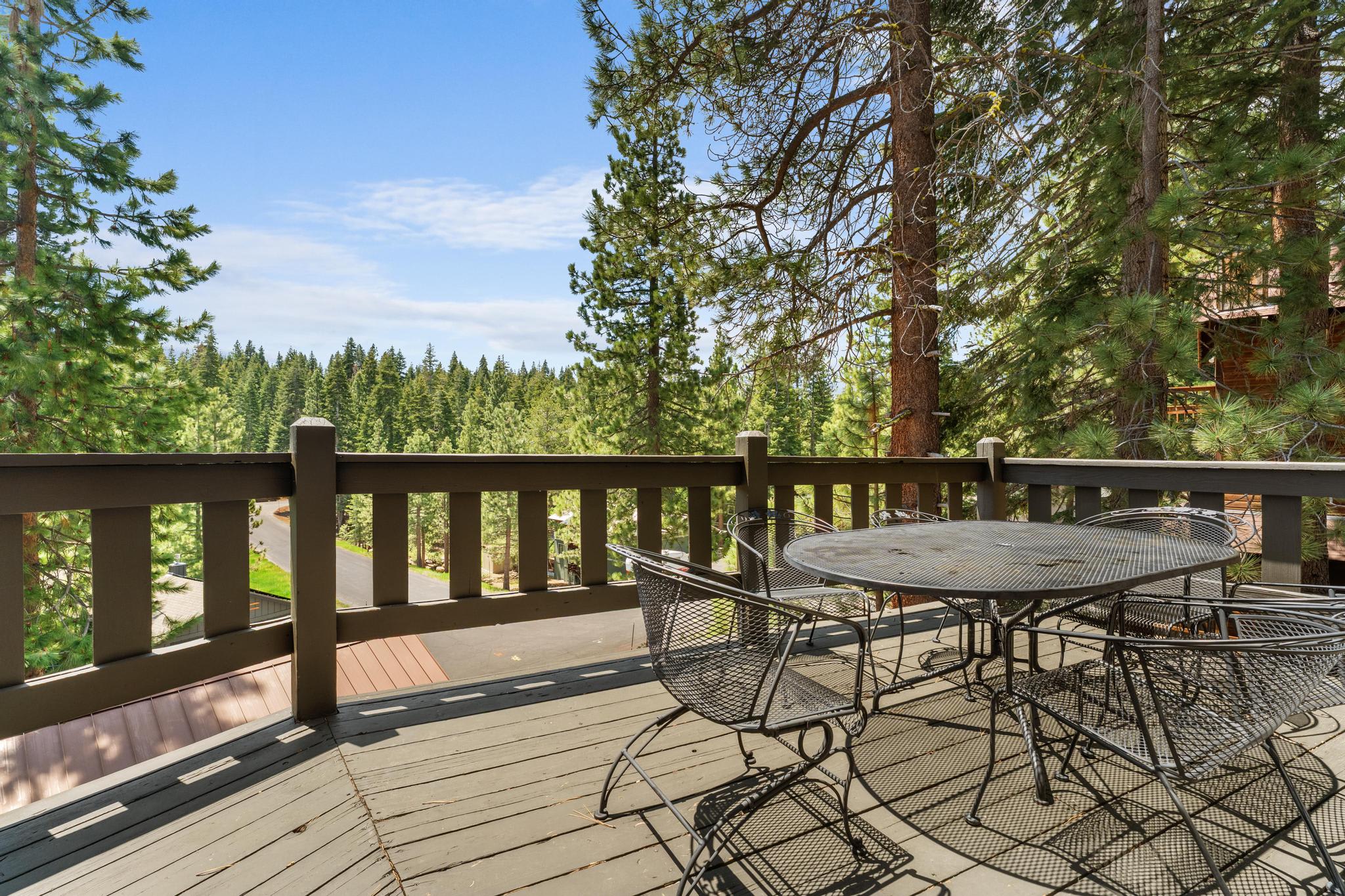 Deck with table overlooking pine trees at a Tahoe Vista vacation rental, offering a tranquil forest view.
