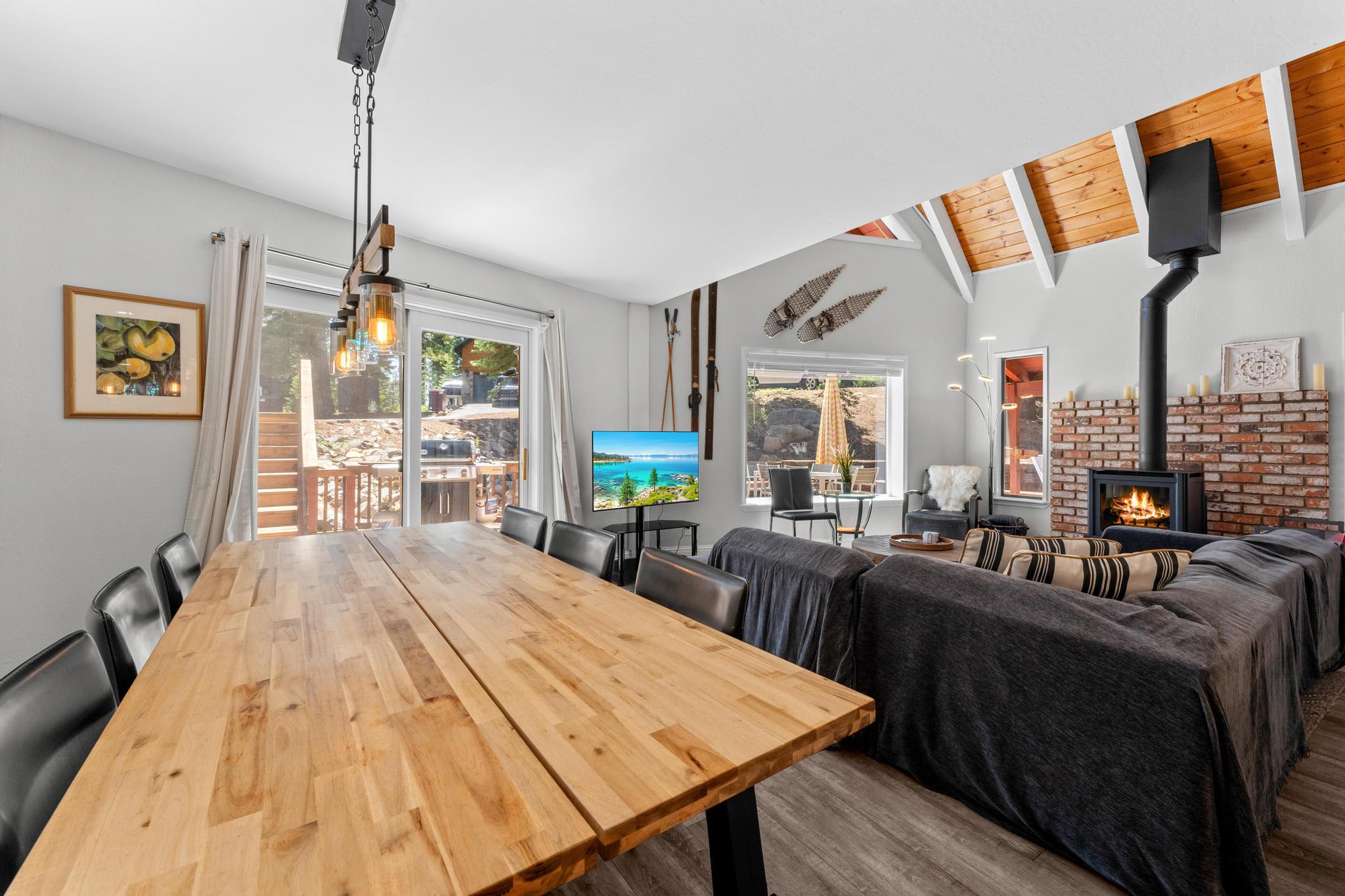 Cozy Tahoe Vista vacation rental with modern dining area, fireplace, and deck access through large windows.