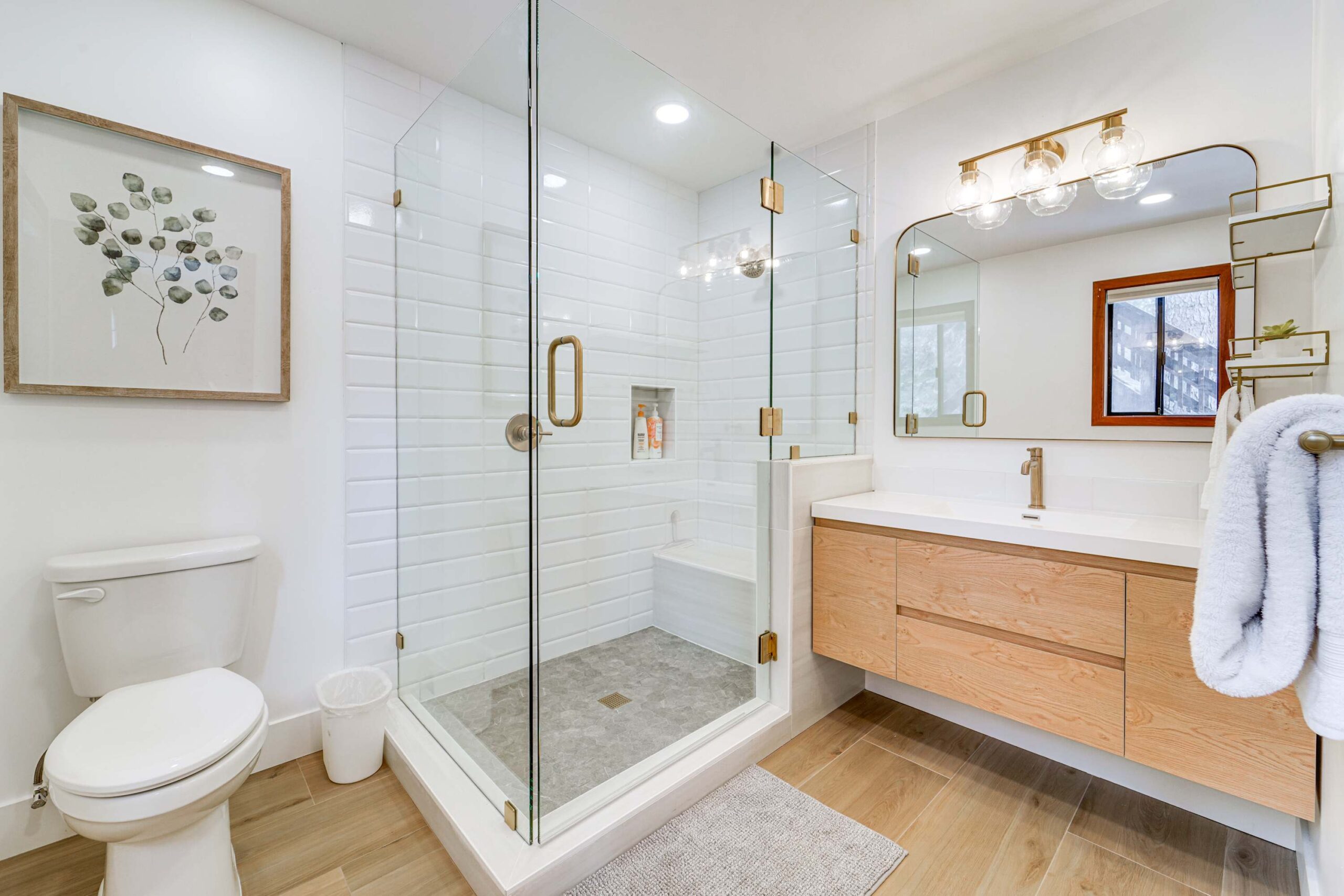 Modern bathroom in a Truckee vacation rental with glass shower, wooden vanity, and white walls.