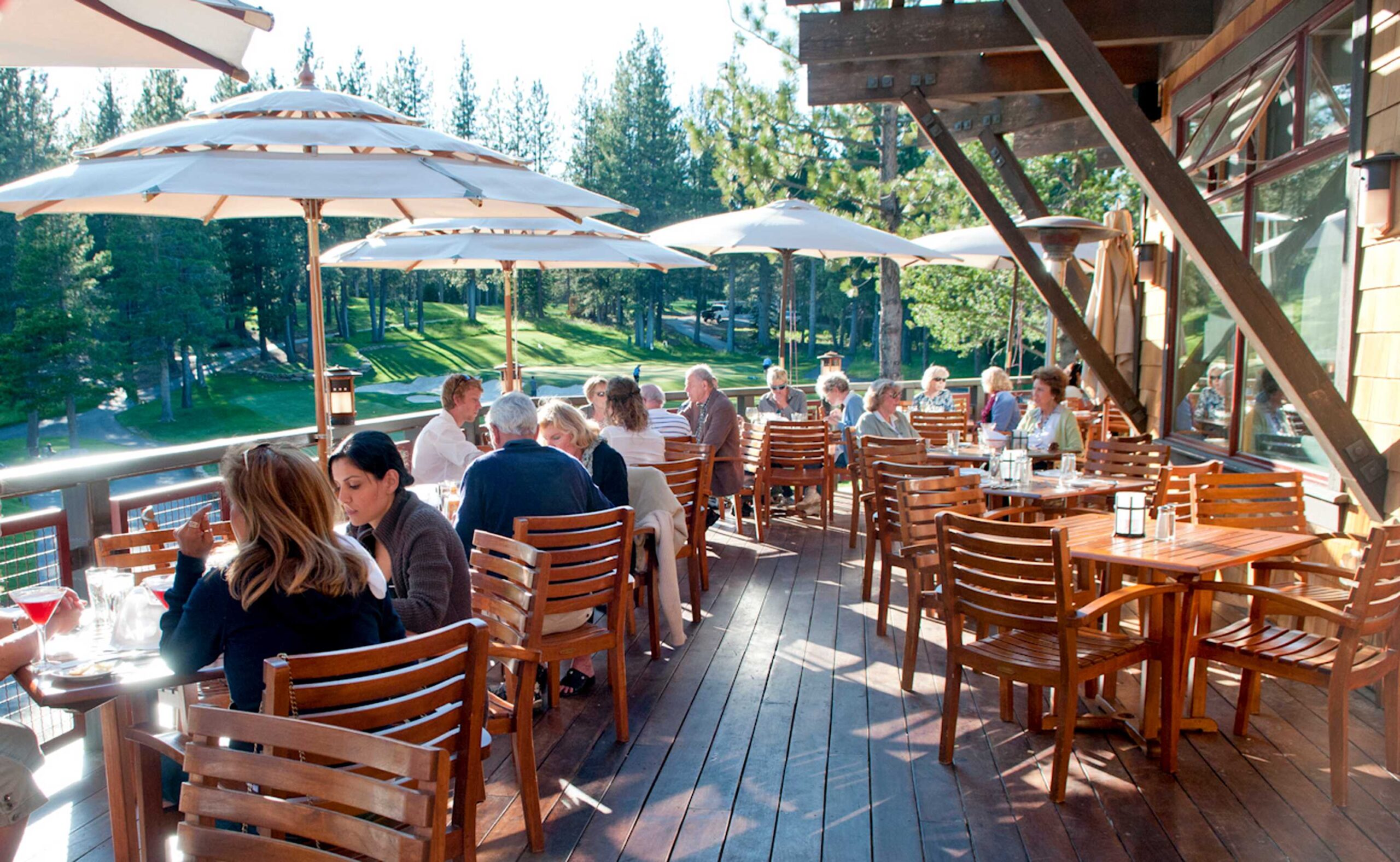 Outdoor dining area at a Truckee vacation rental, guests enjoy meals on a sunny deck with forest views.