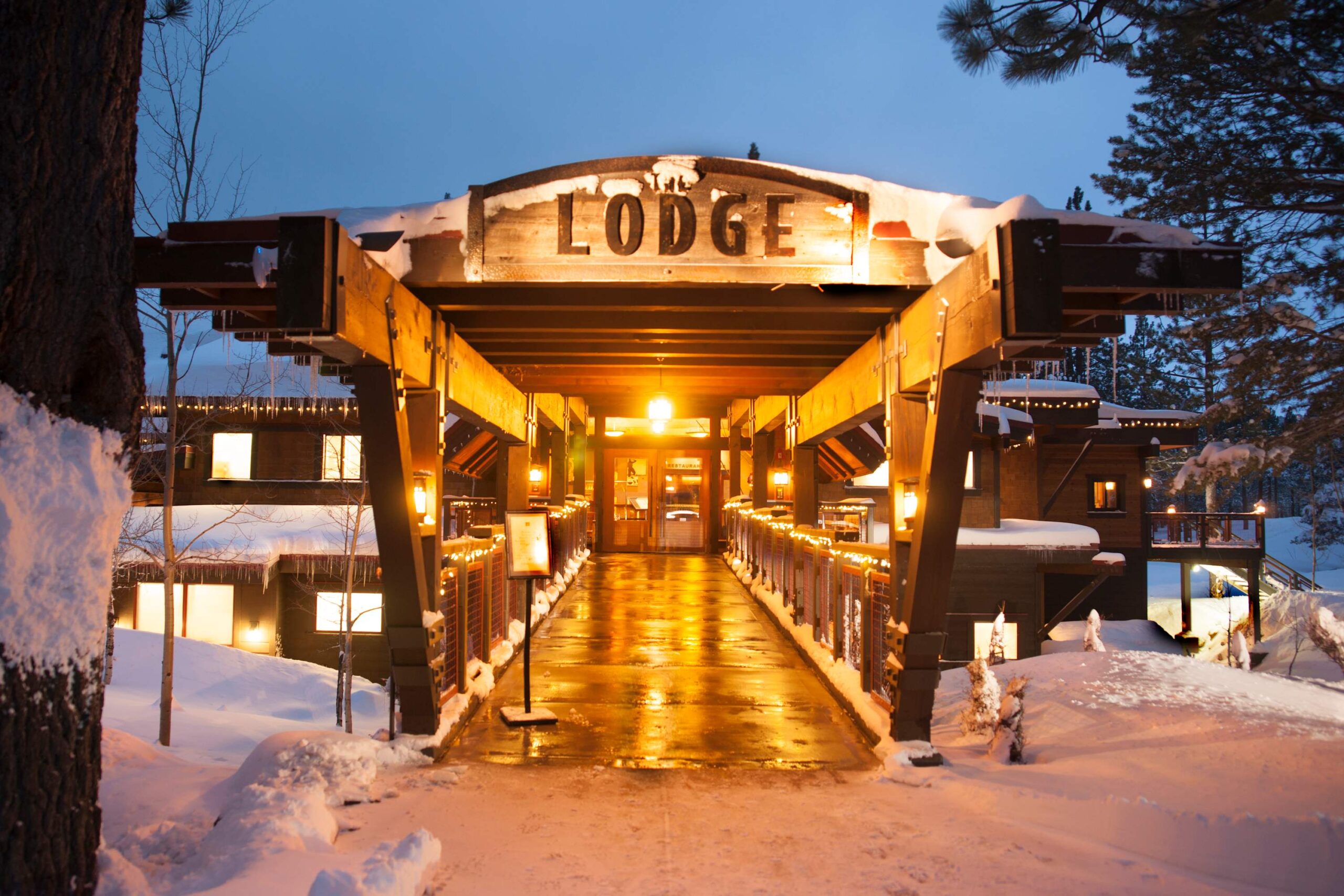 Snowy entrance to a warmly lit lodge in Truckee, ideal for a cozy vacation rental experience.