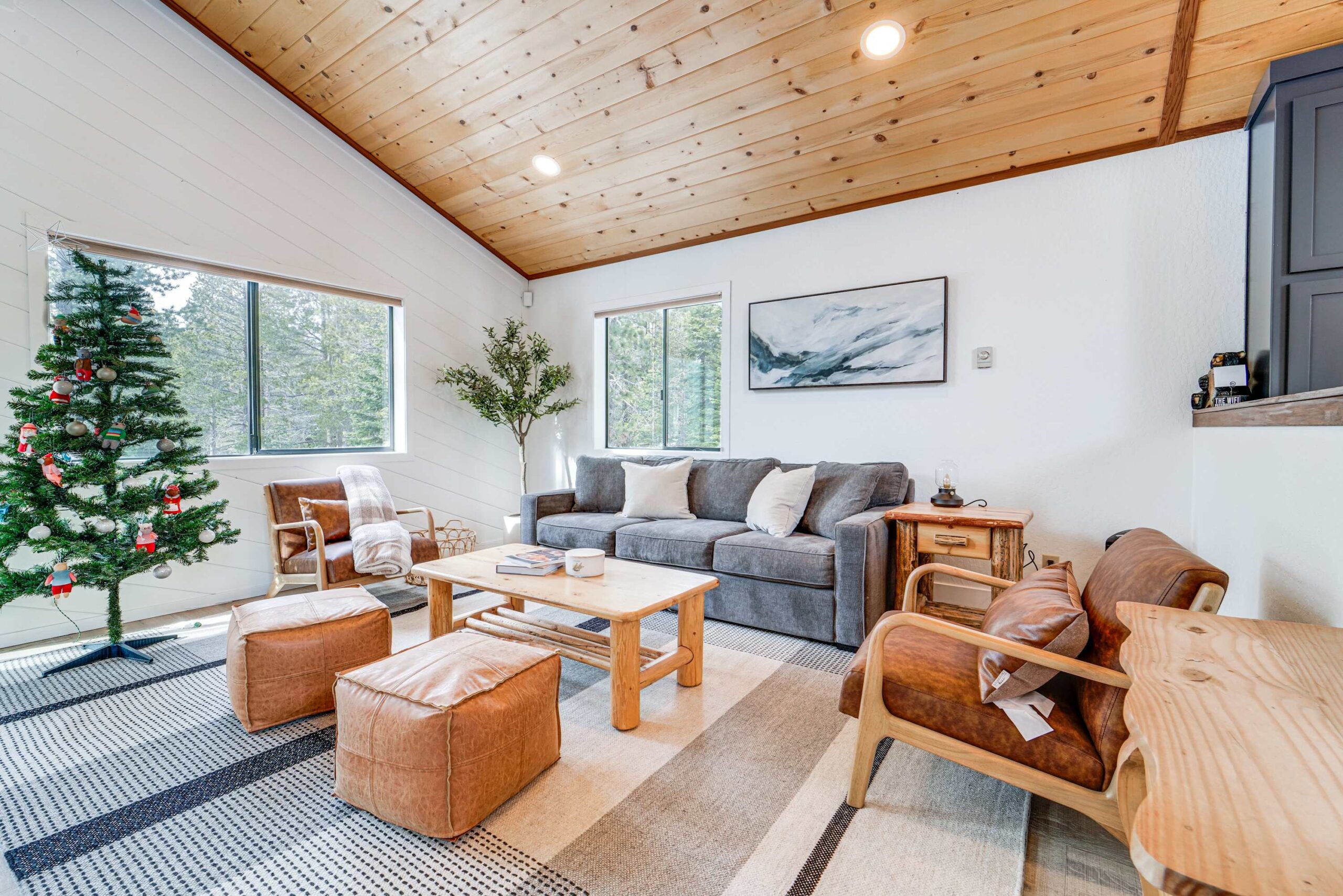 Cozy Truckee vacation rental living room with wood ceiling, modern furniture, and a decorated Christmas tree by the window.