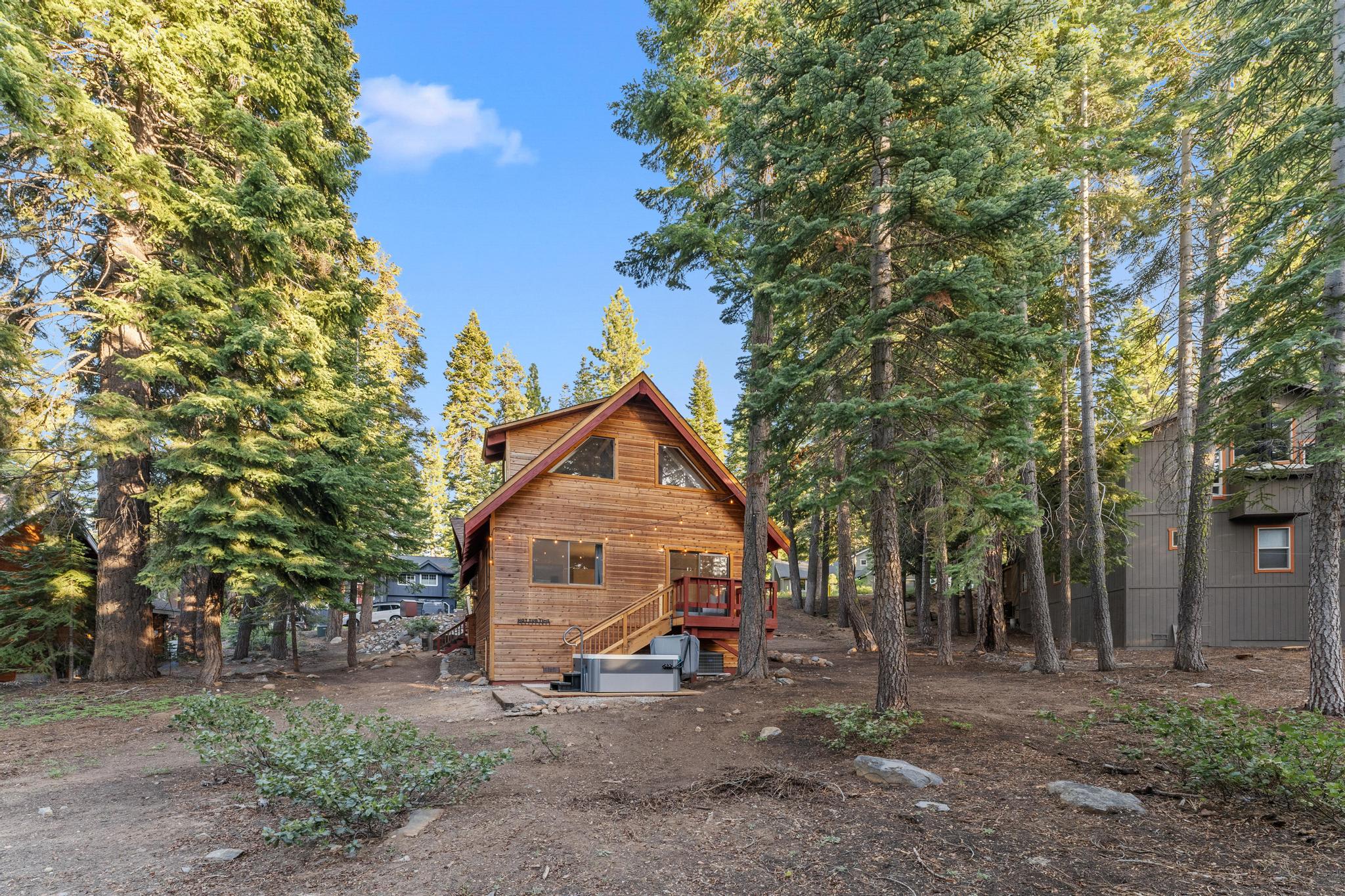 Wooden cabin vacation rental in Tahoe Vista surrounded by tall pine trees and natural landscape.