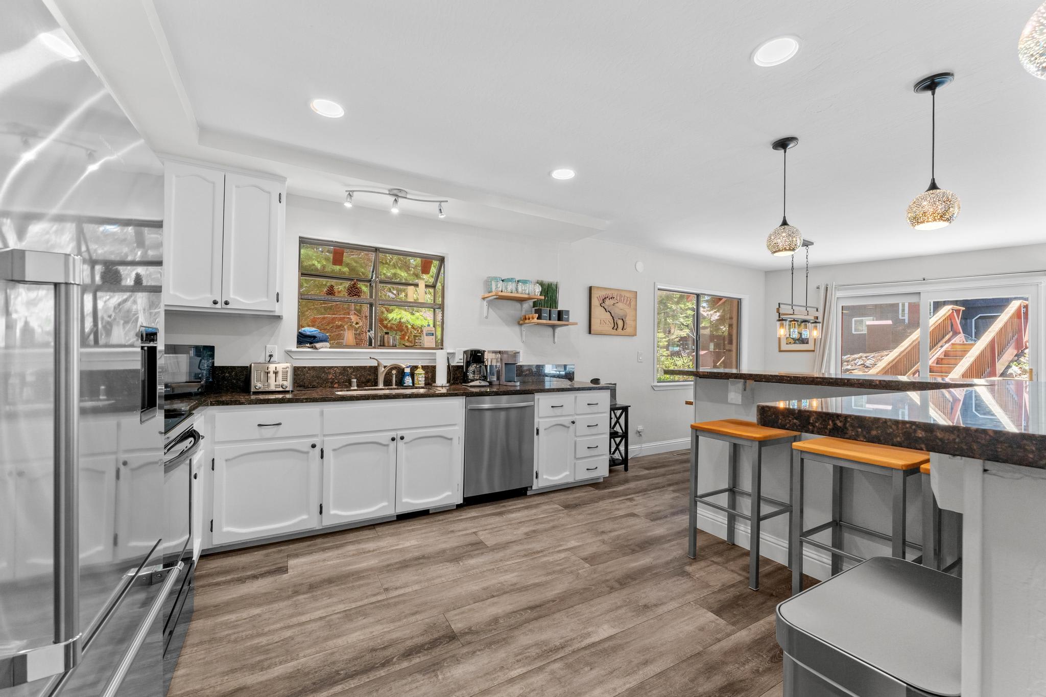 Modern kitchen in a Tahoe Vista vacation rental, featuring sleek appliances, white cabinets, and bright natural lighting.