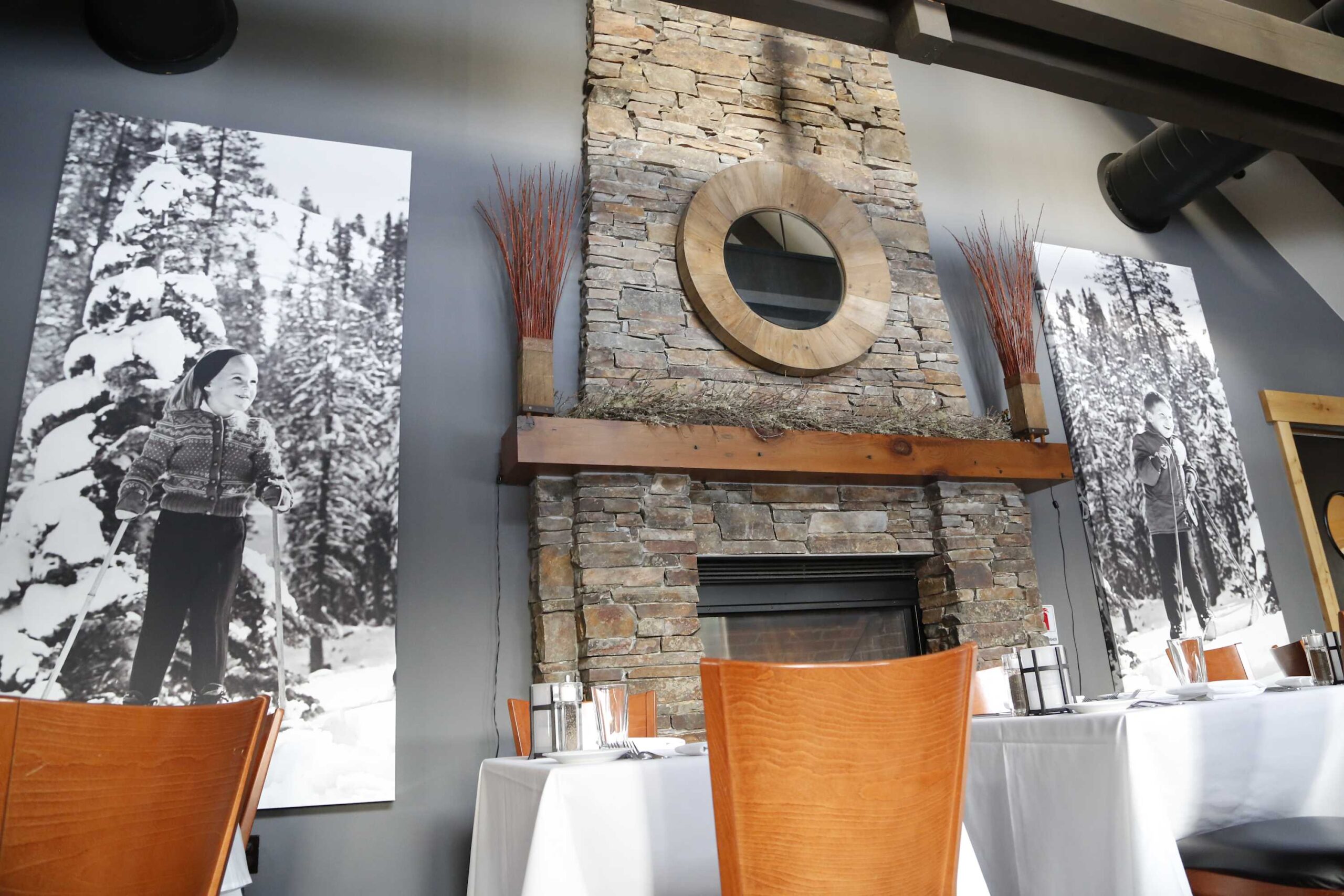 Cozy Truckee vacation rental with stone fireplace, dining table, and winter-themed black-and-white photos on the walls.
