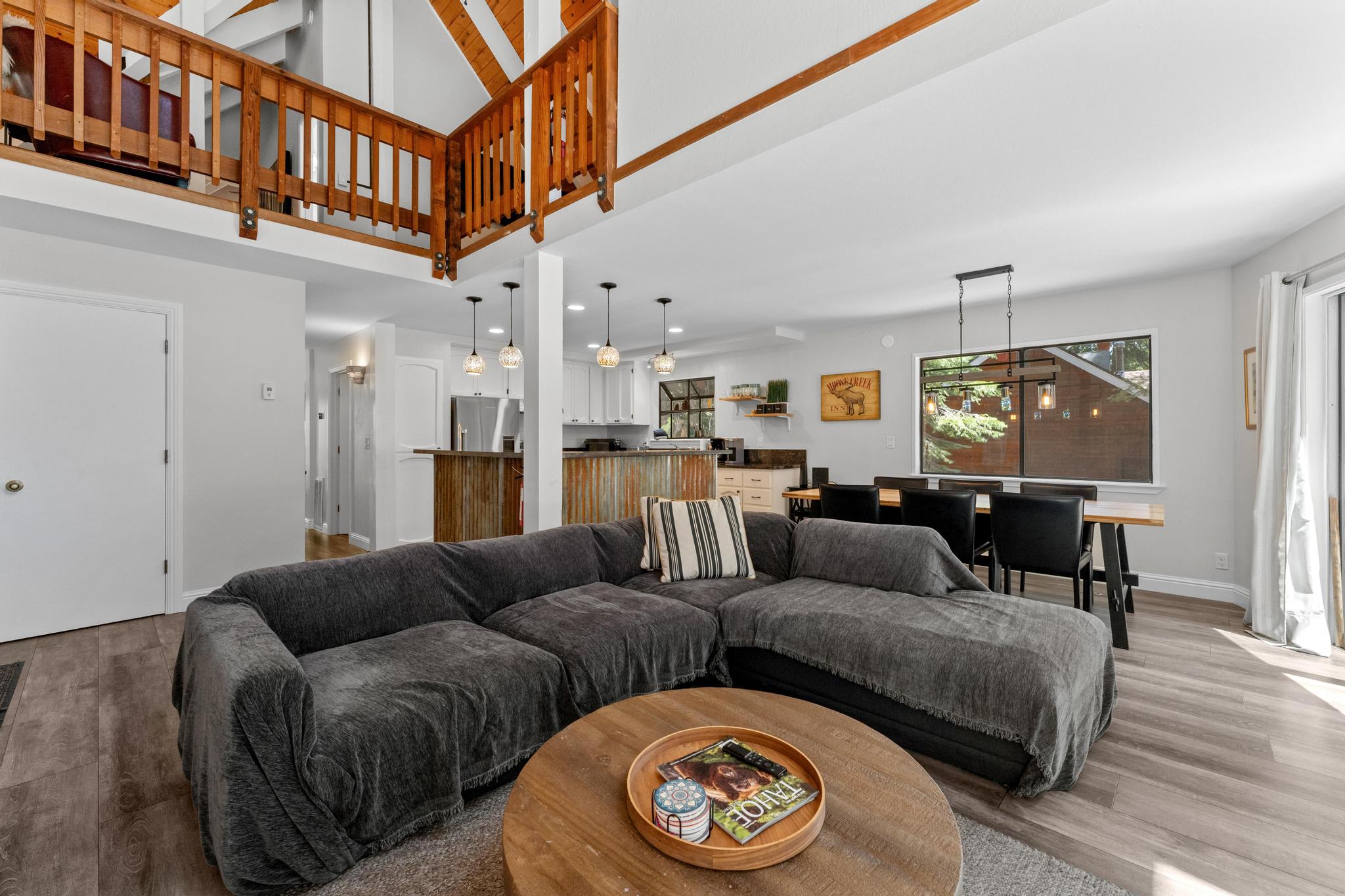 Spacious Tahoe Vista vacation rental with cozy gray sofa, wooden accents, modern kitchen, and large dining table.