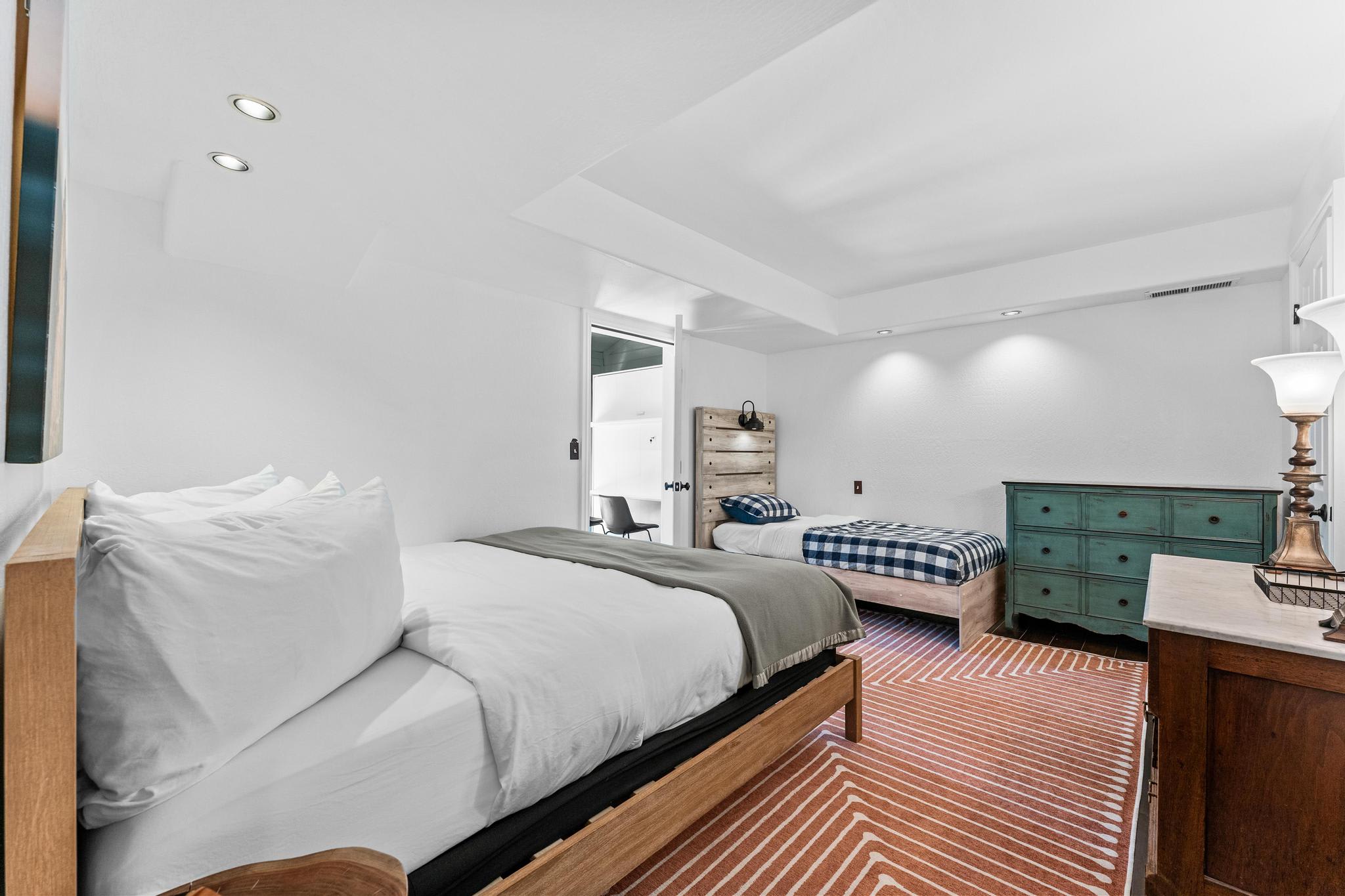 Bedroom in a Truckee vacation rental featuring a double and a single bed, a dresser, and modern lighting.