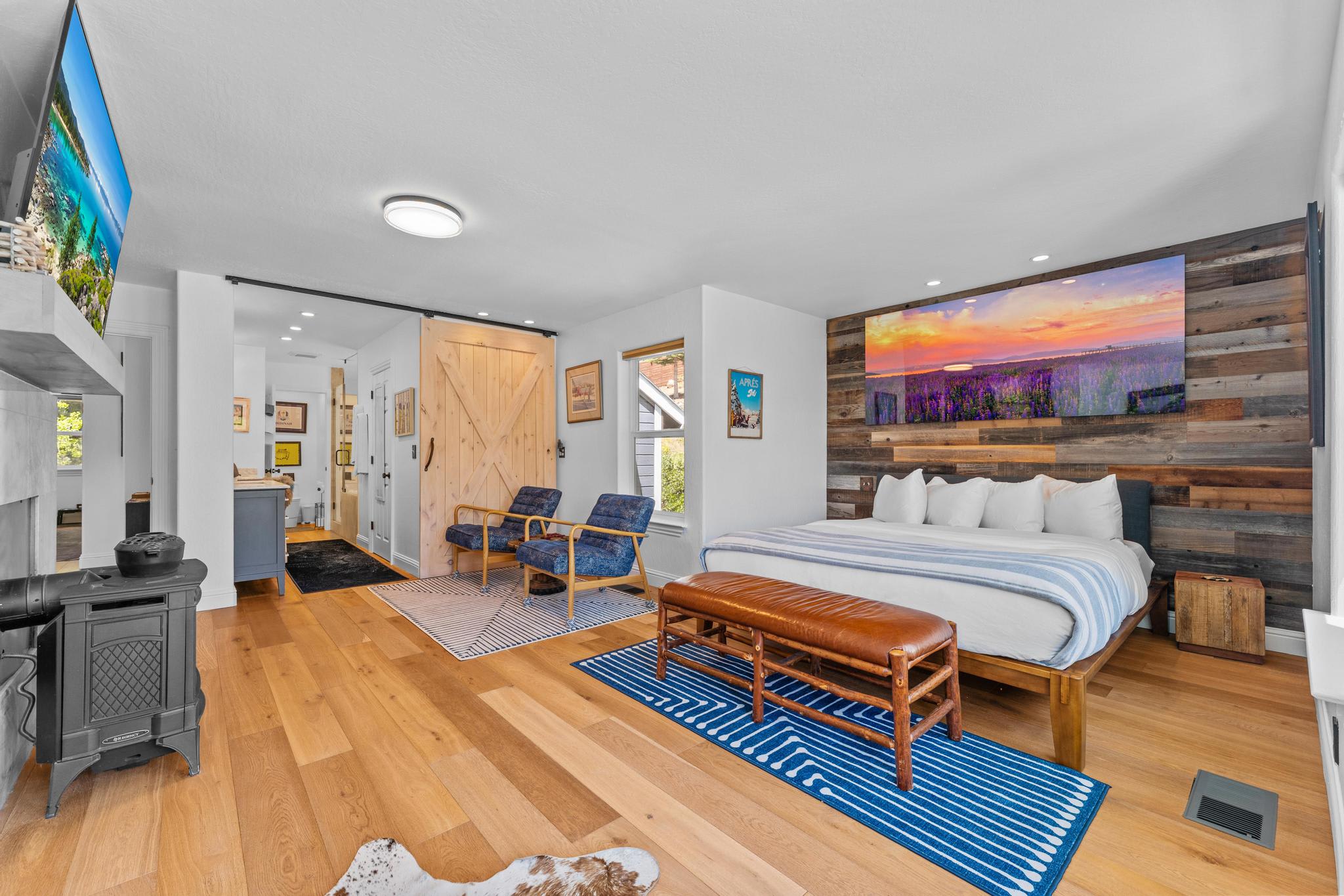 Modern Truckee vacation rental bedroom with wooden floors, cozy bed, blue chairs, and warm decor.