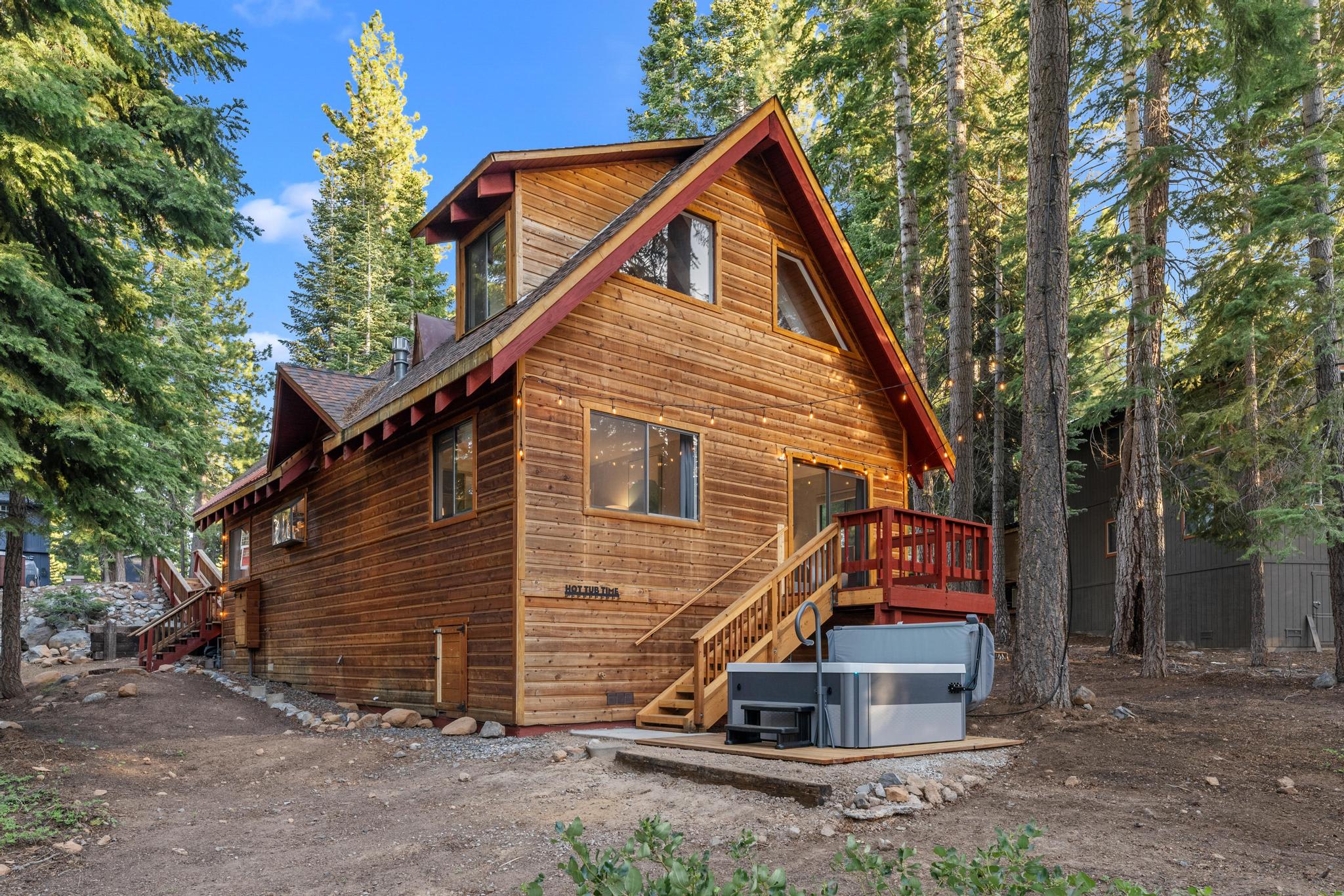 Rustic wooden cabin, a vacation rental in Tahoe Vista, nestled among tall trees with a hot tub on the deck.