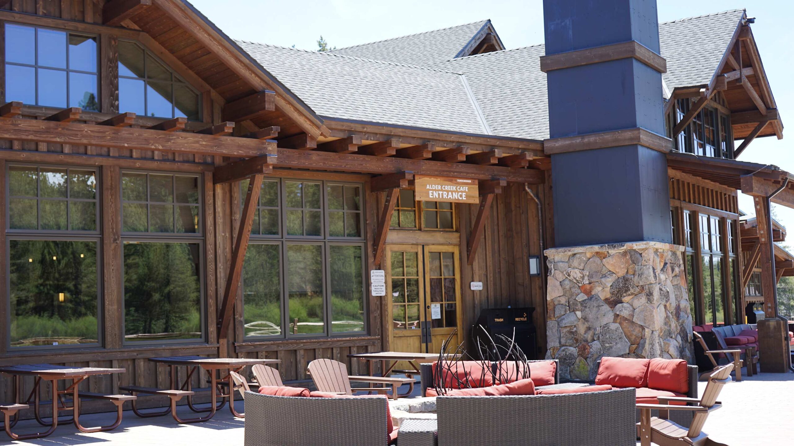 Rustic vacation rental in Truckee with wood exterior, stone chimney, and outdoor seating near Alder Creek Café entrance.
