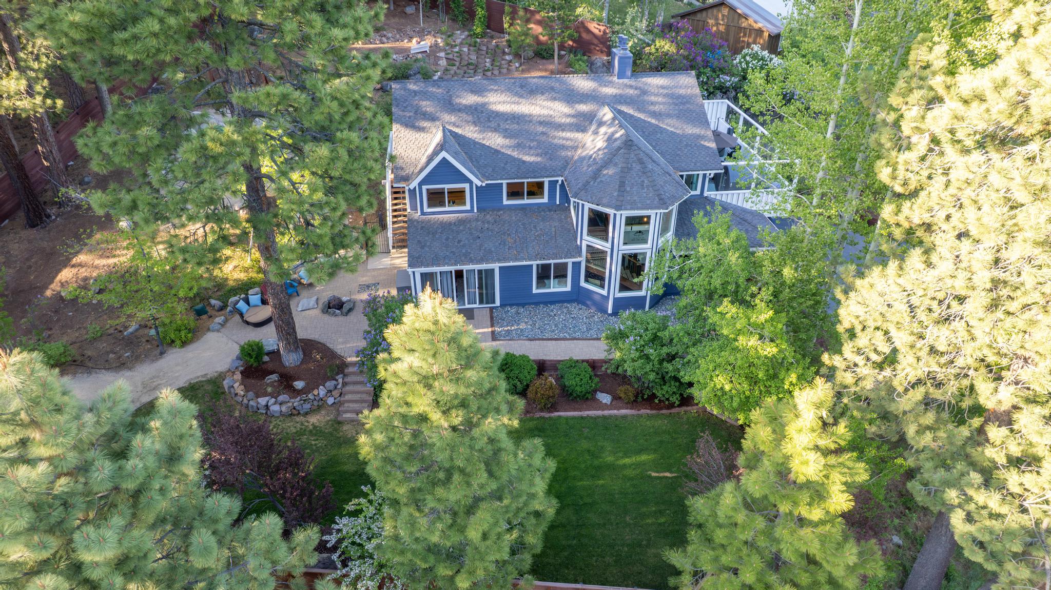 Aerial view of a charming blue house surrounded by trees, a perfect vacation rental in Truckee.