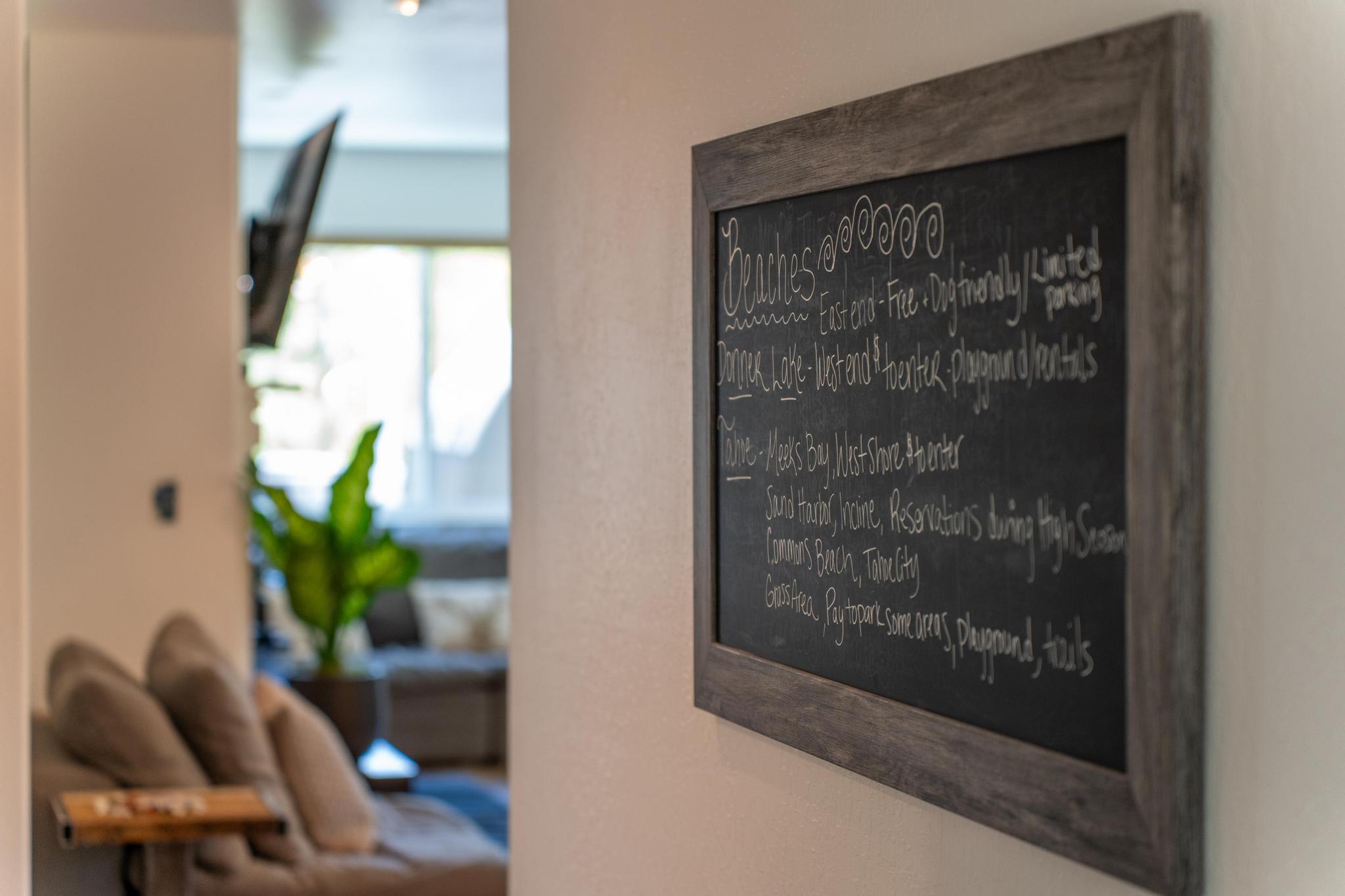 Chalkboard with local attractions in a cozy Truckee vacation rental, soft couch and TV in the background.