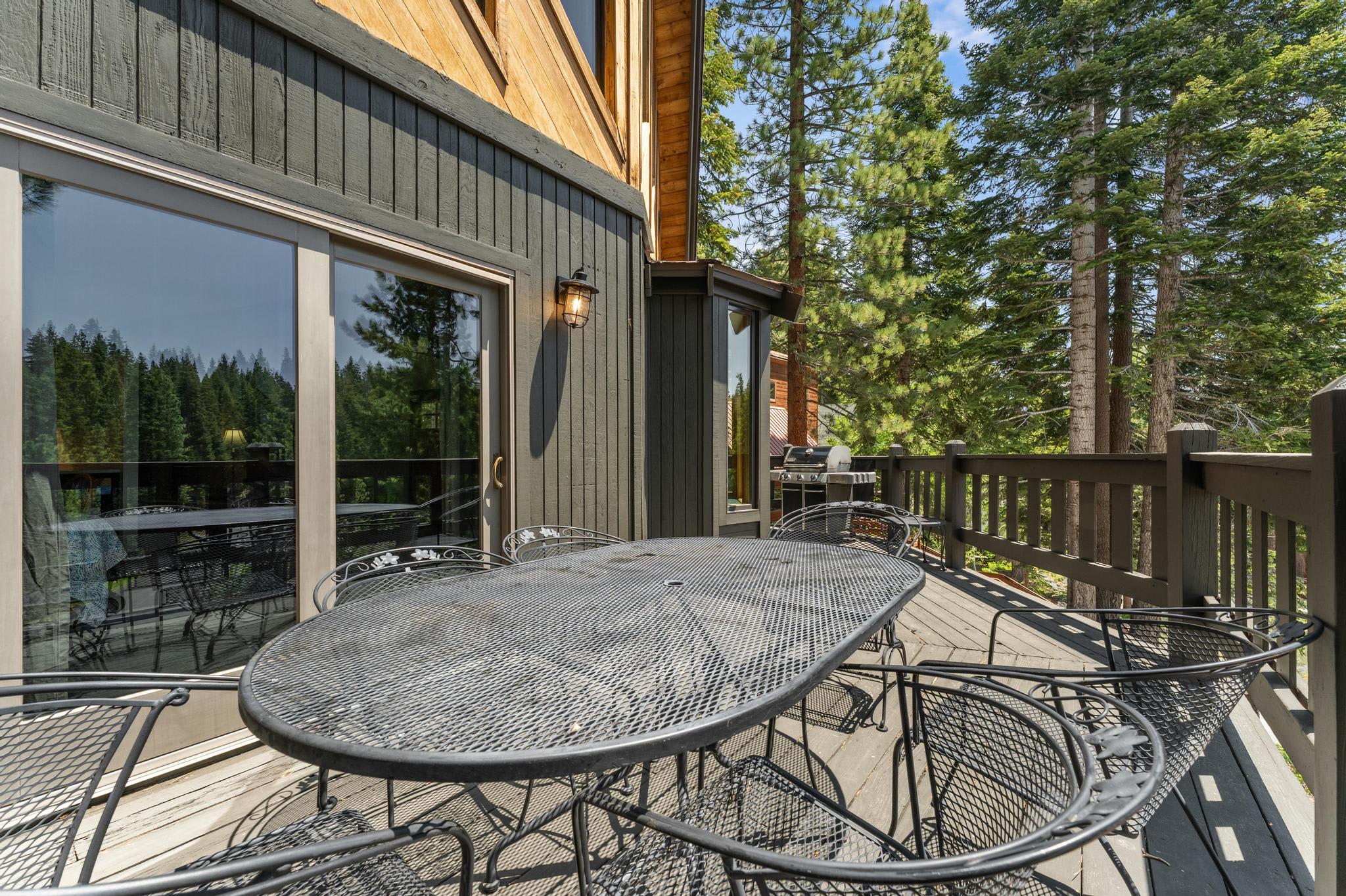Outdoor deck with metal furniture at a vacation rental in Tahoe Vista, surrounded by lush trees and natural beauty.
