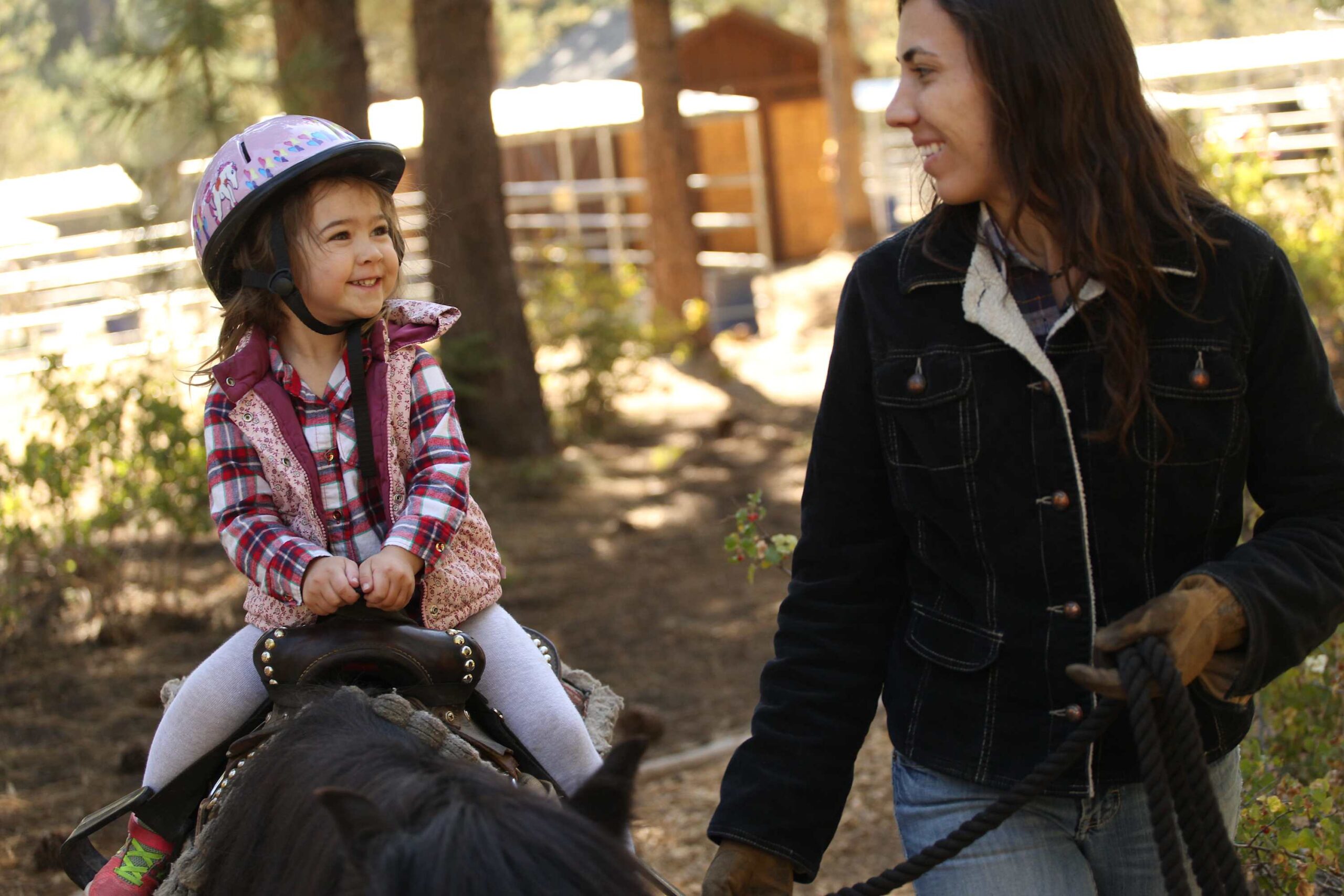 Child on pony with adult in forest, enjoying a vacation rental experience in Truckee.