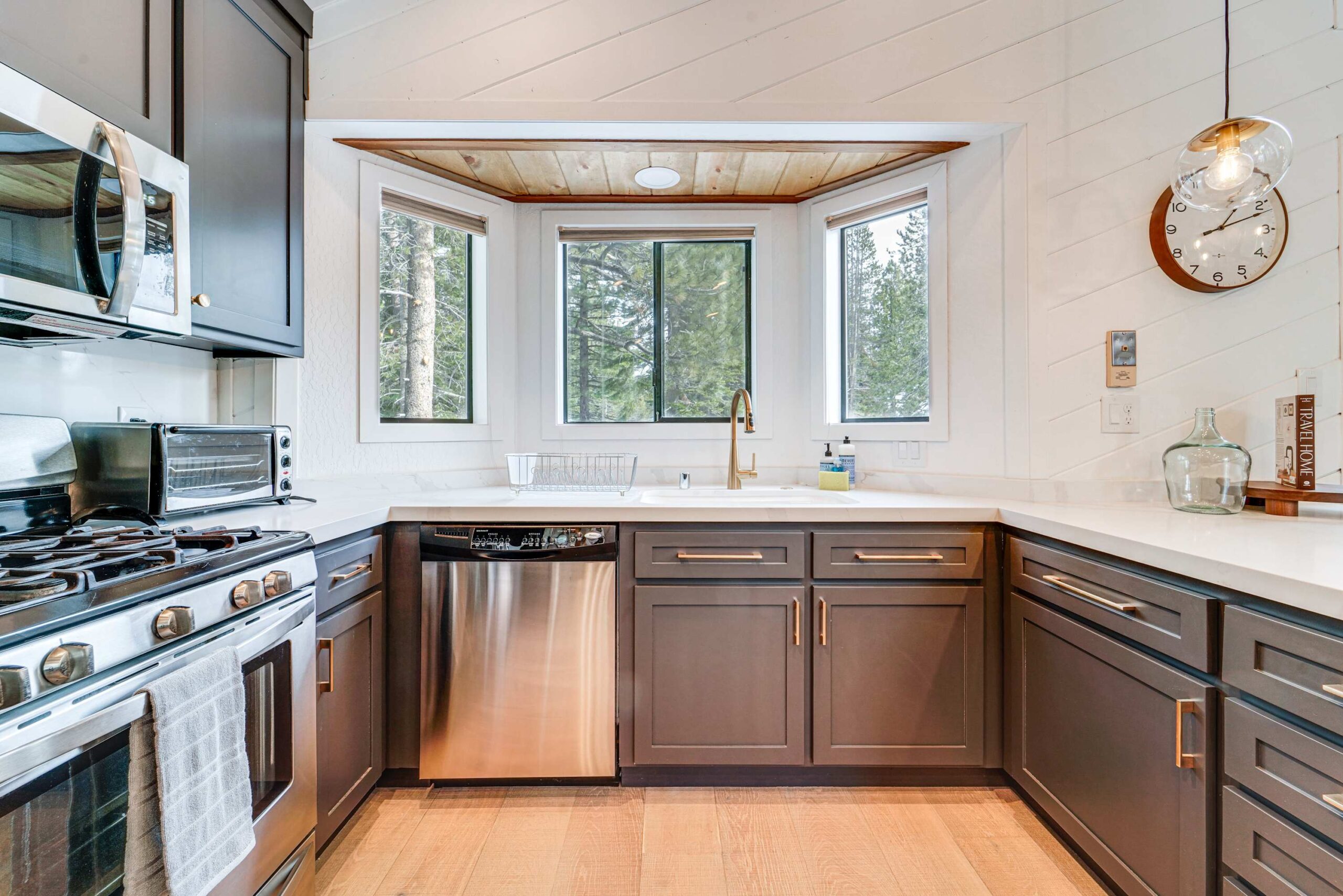 Modern kitchen in a Truckee vacation rental, featuring stainless steel appliances, dark cabinets, and large windows.