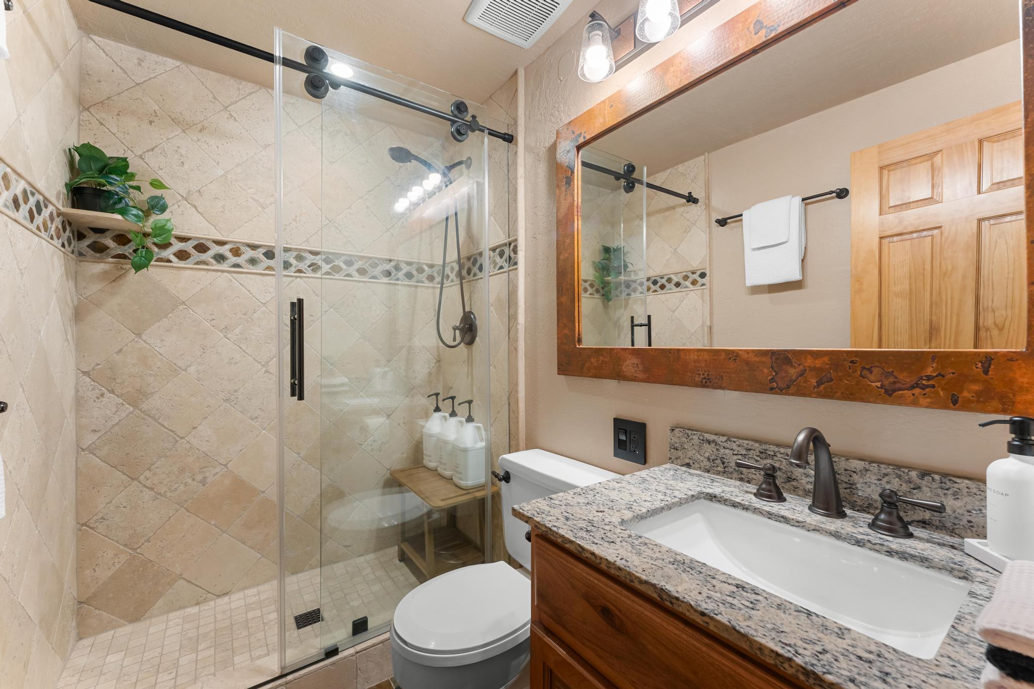 Modern bathroom in a Truckee vacation rental with tiled shower, glass door, granite countertop, and wooden accents.