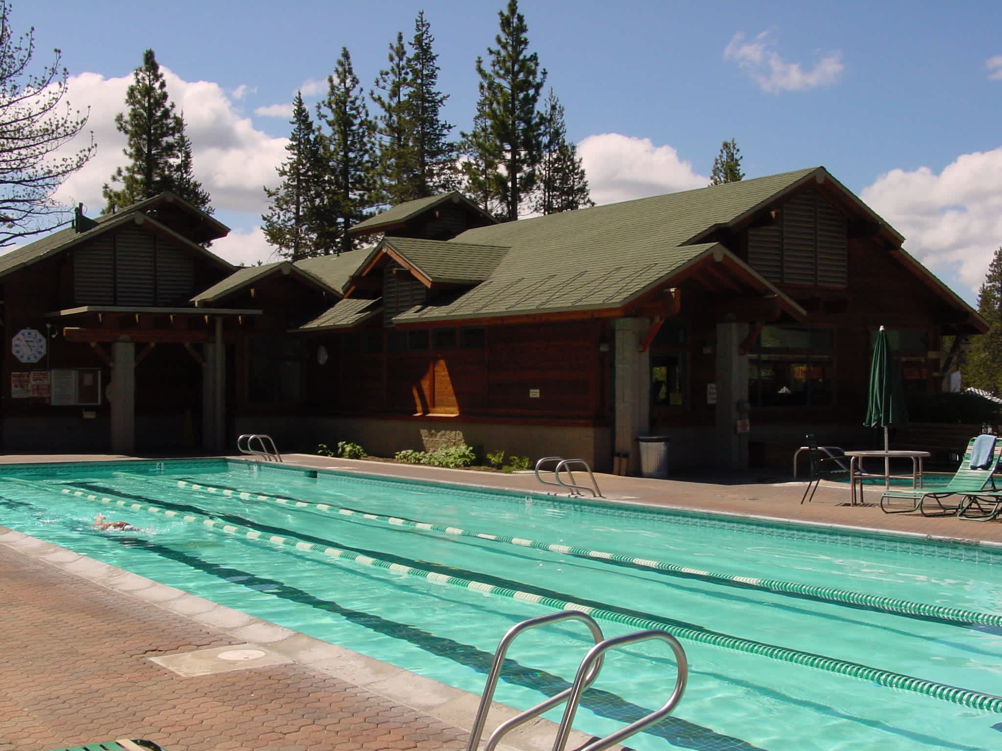 Outdoor pool at a vacation rental in Truckee, surrounded by pine trees and a rustic lodge-style building.