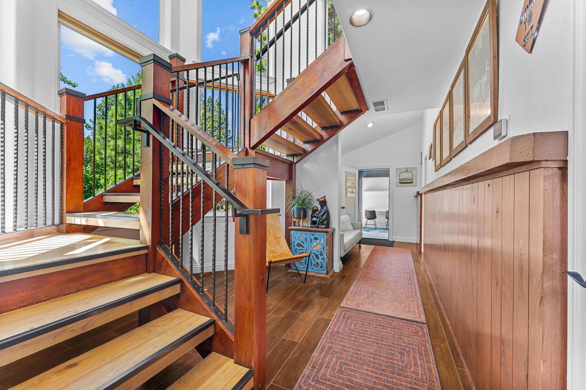 Stunning wooden staircase in a Truckee vacation rental, featuring modern decor and large windows with outdoor views.