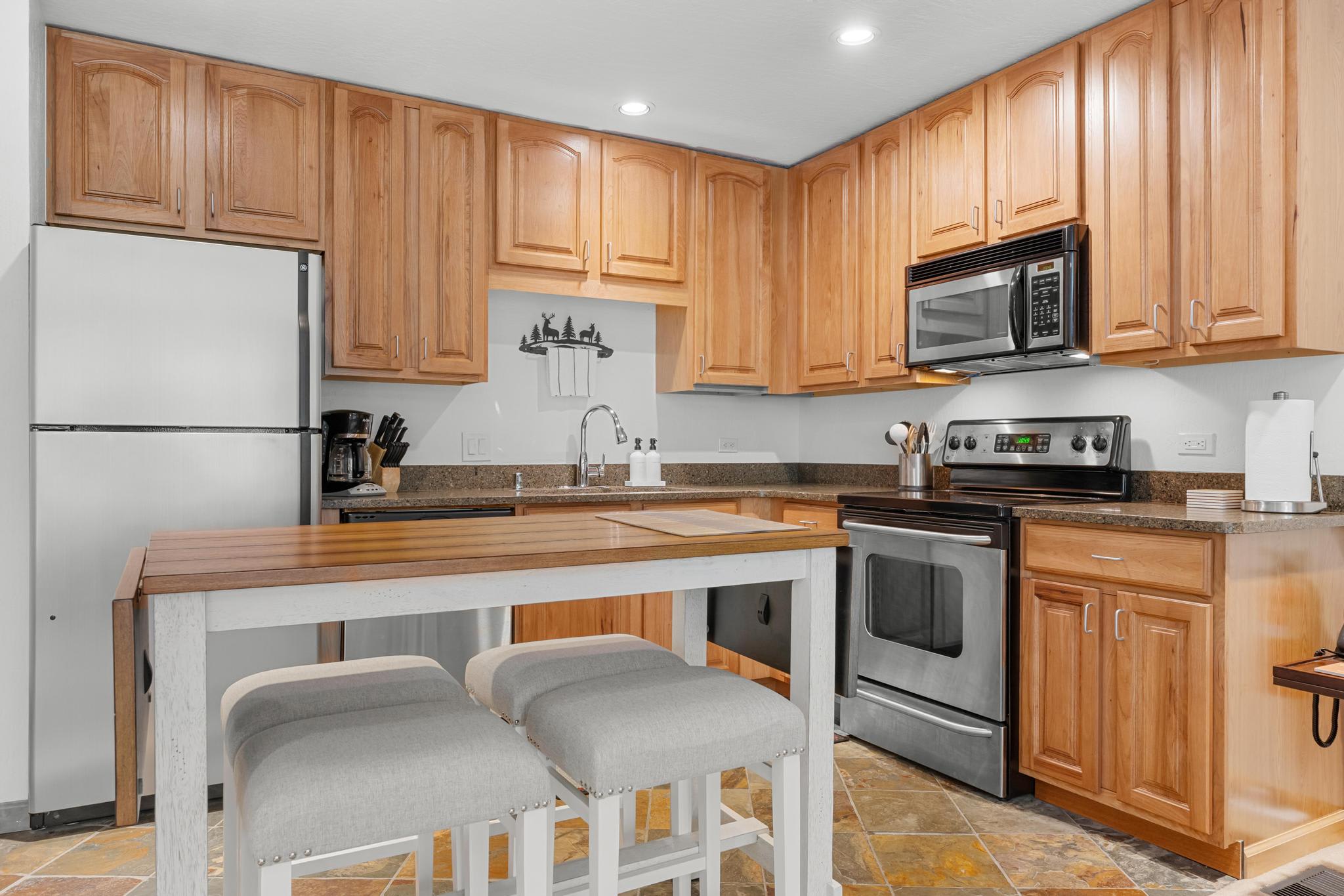 Cozy kitchen in a Truckee vacation rental with wooden cabinets, modern appliances, and a small dining area.