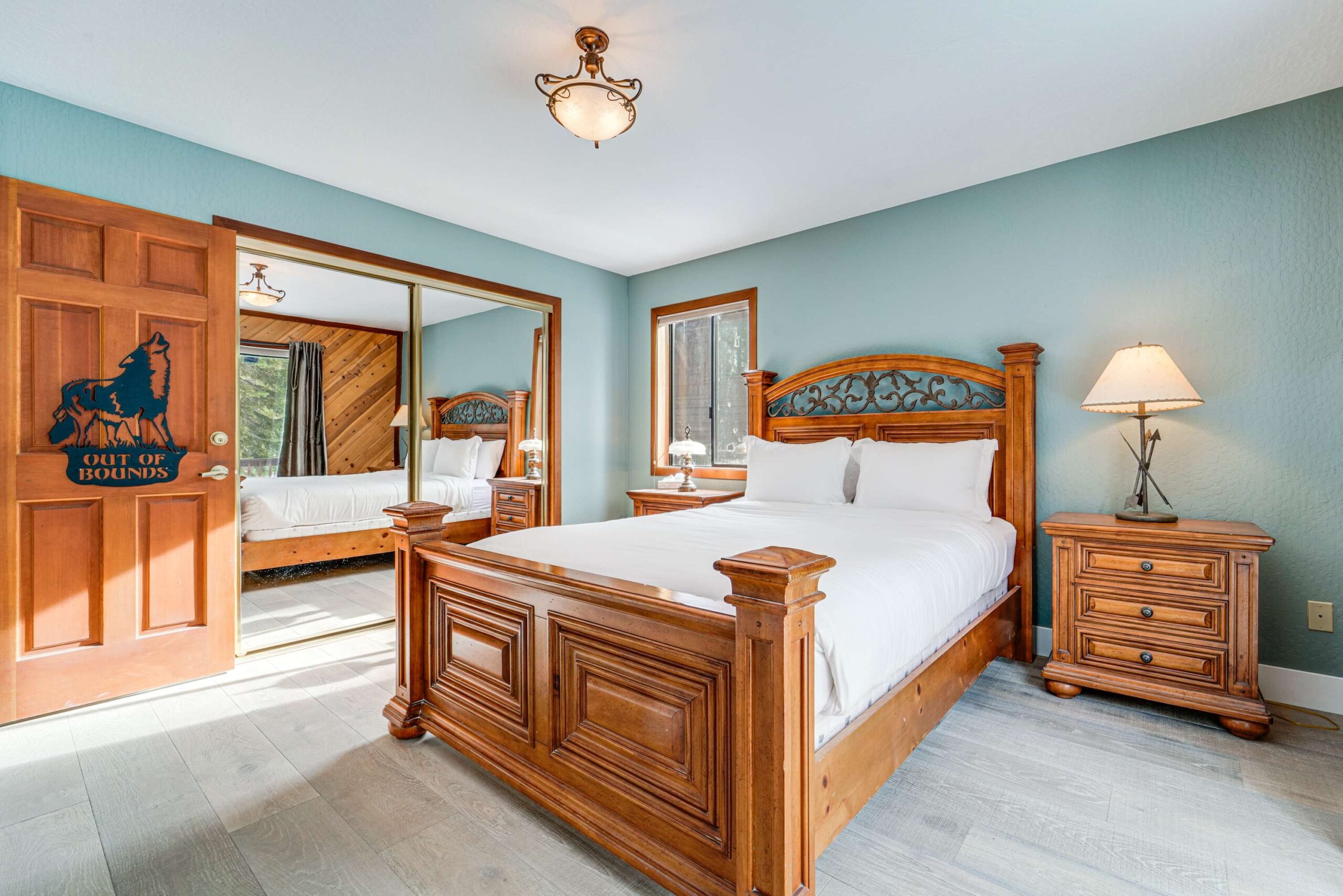Cozy bedroom with wooden furniture in a Truckee vacation rental, featuring a plush bed, lamp, and mirrored closet.