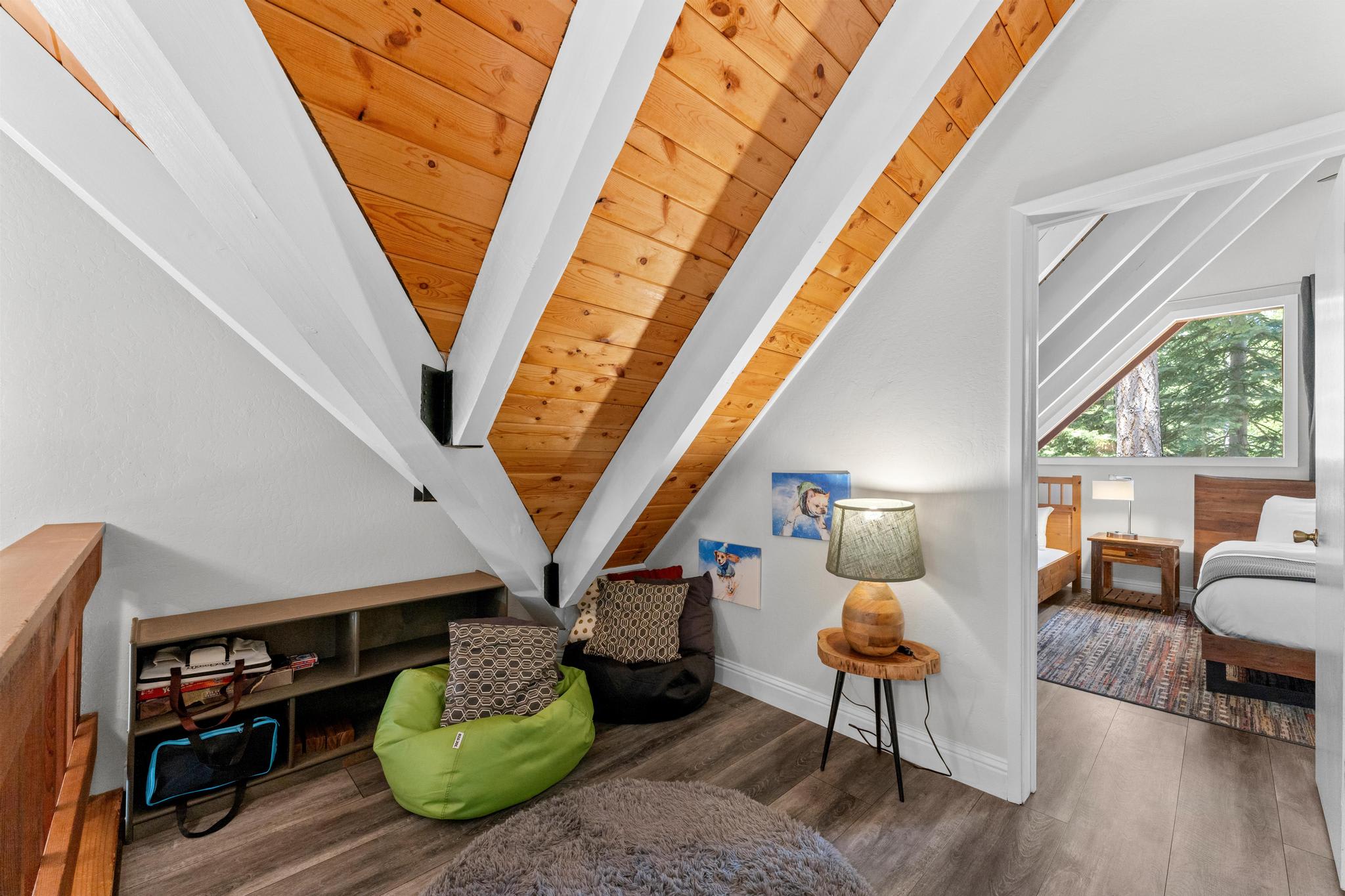Cozy attic room in Tahoe Vista vacation rental with wooden ceiling, bean bags, and plush pillows near bedroom.