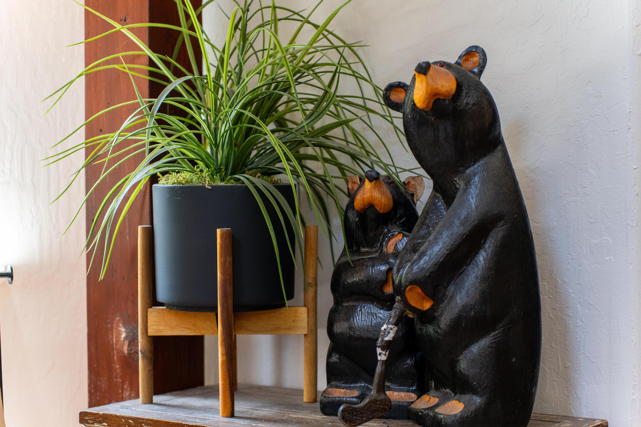 Wooden bear sculptures and a potted plant on a shelf in a Truckee vacation rental.