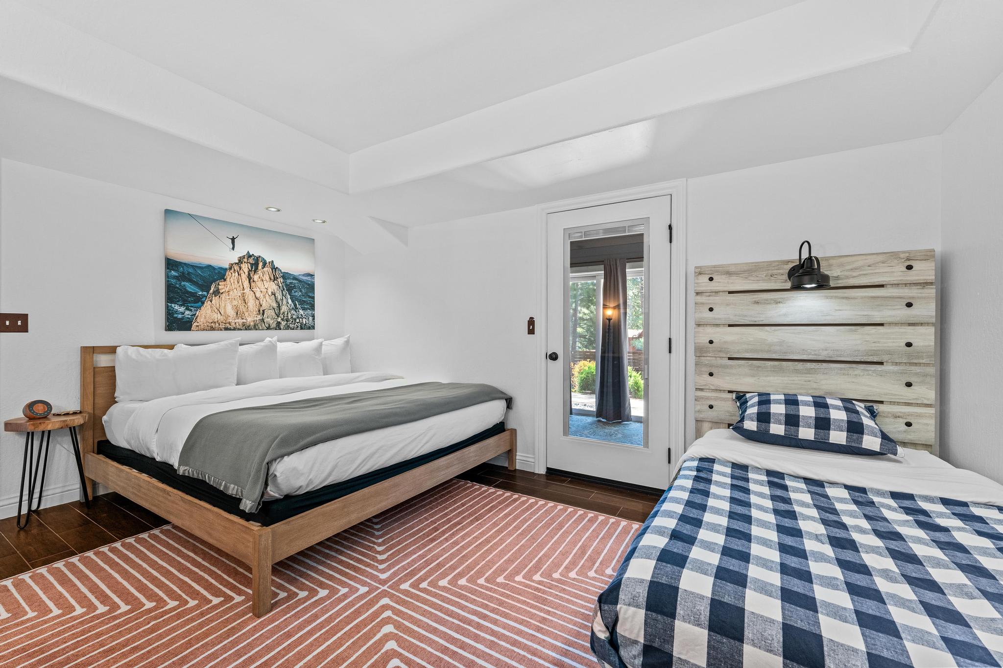 Bedroom in Truckee vacation rental with a large bed, side table, and patio door, featuring mountain artwork.