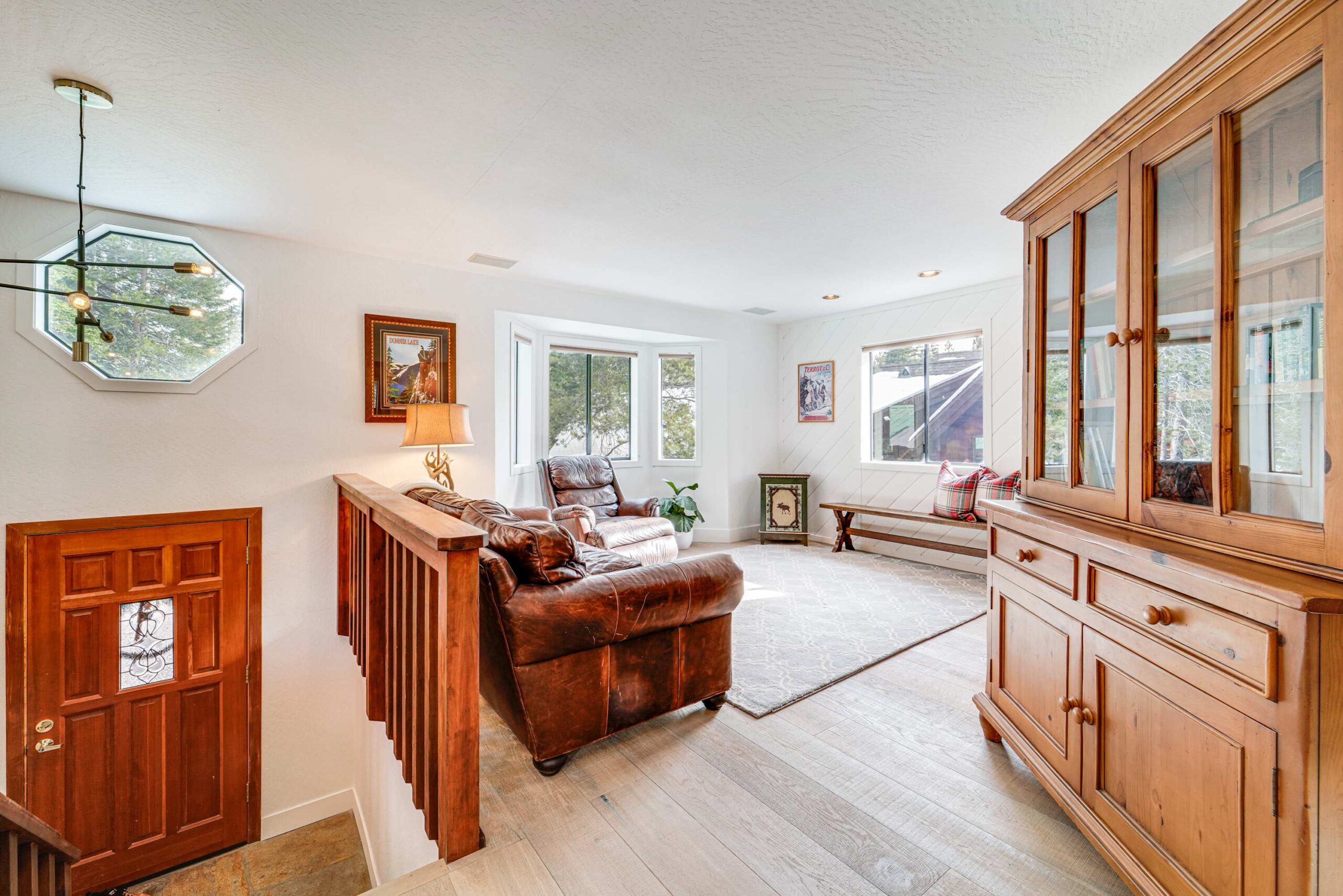 Cozy Truckee vacation rental living room with leather chair, wooden furniture, large windows, and natural light.