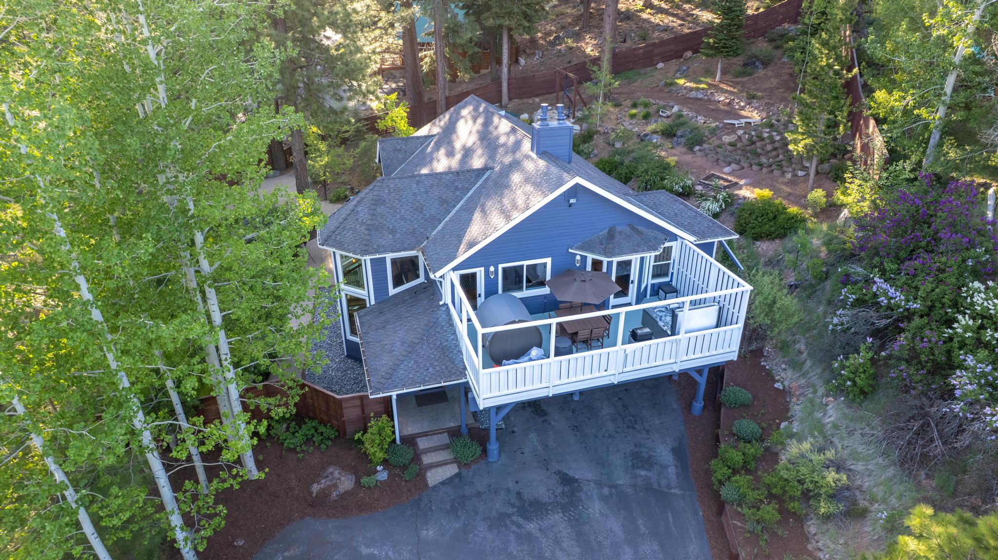 Aerial view of a Truckee vacation rental surrounded by lush trees, featuring a spacious deck with outdoor seating.