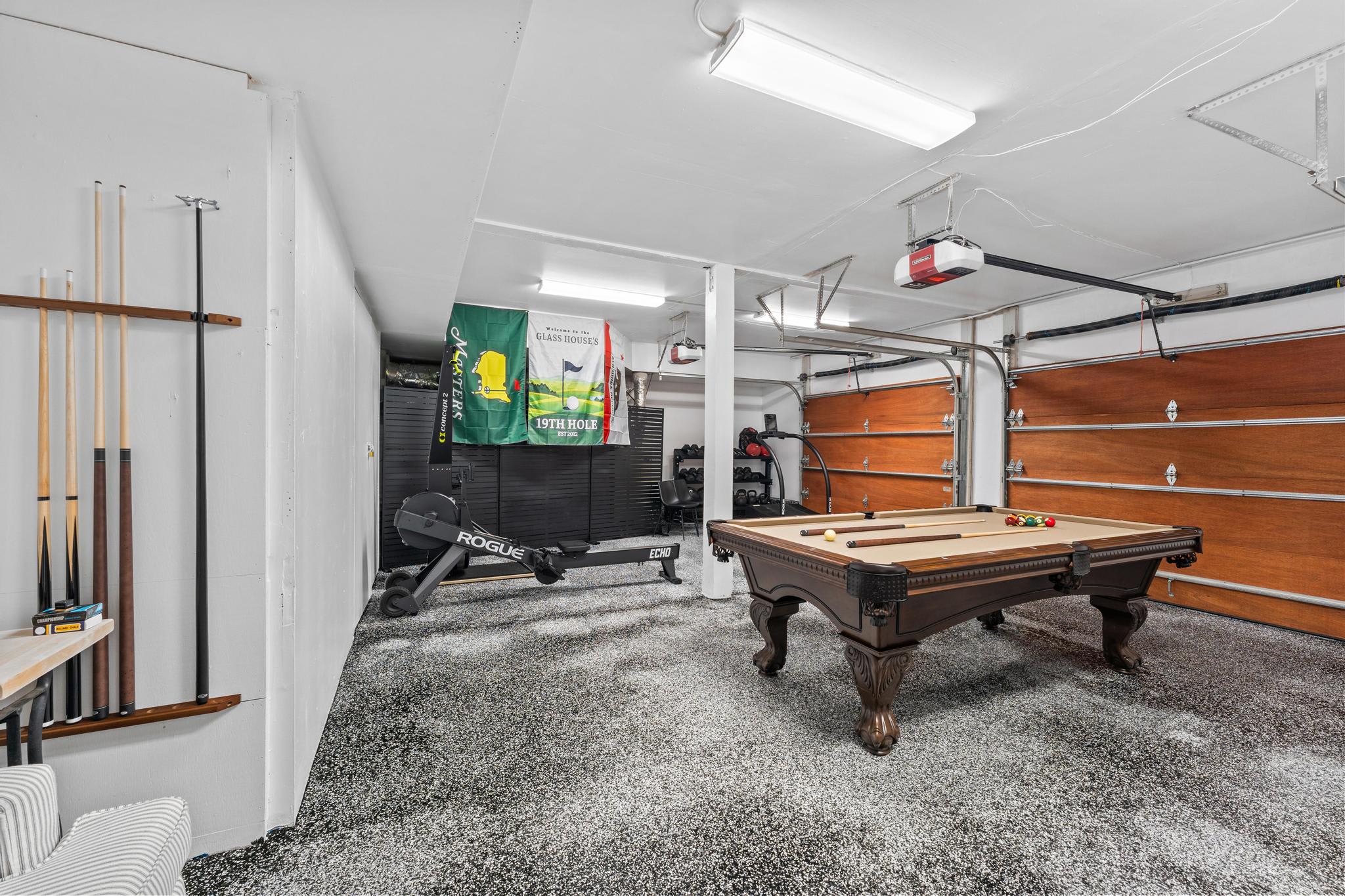 Game room in Truckee vacation rental with pool table, gym equipment, and colorful decor in a spacious garage.