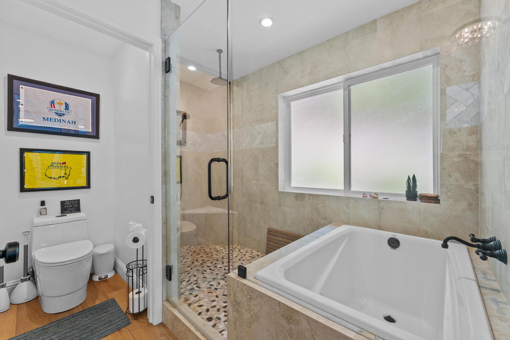 Modern bathroom in Truckee vacation rental with glass shower and large bathtub, decorated with golf-themed artwork.