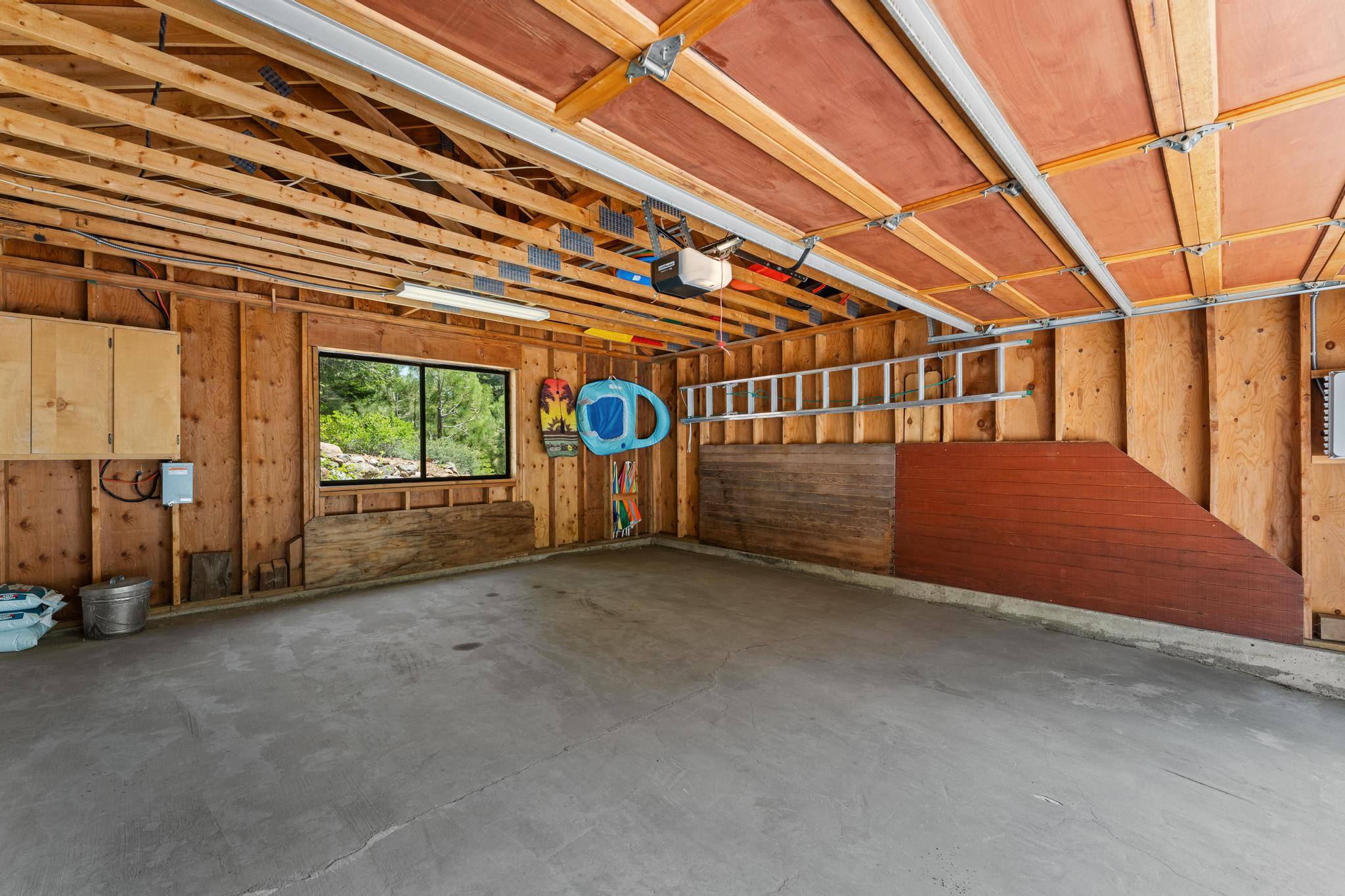 Spacious garage inside Tahoe Vista vacation rental, featuring wooden walls and a window with outdoor view.