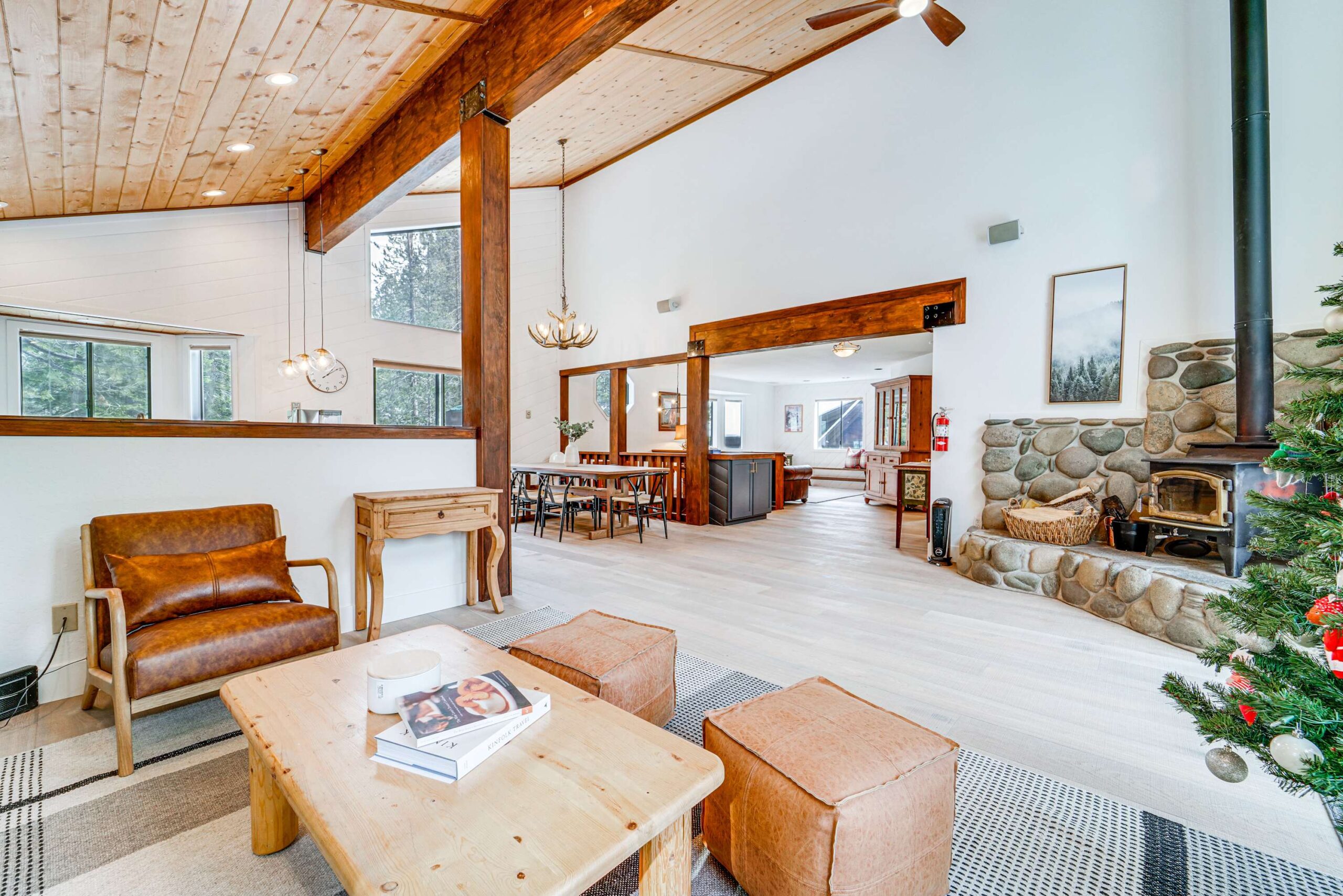 Spacious Truckee vacation rental with cozy living area, stone fireplace, and large windows offering scenic outdoor views.