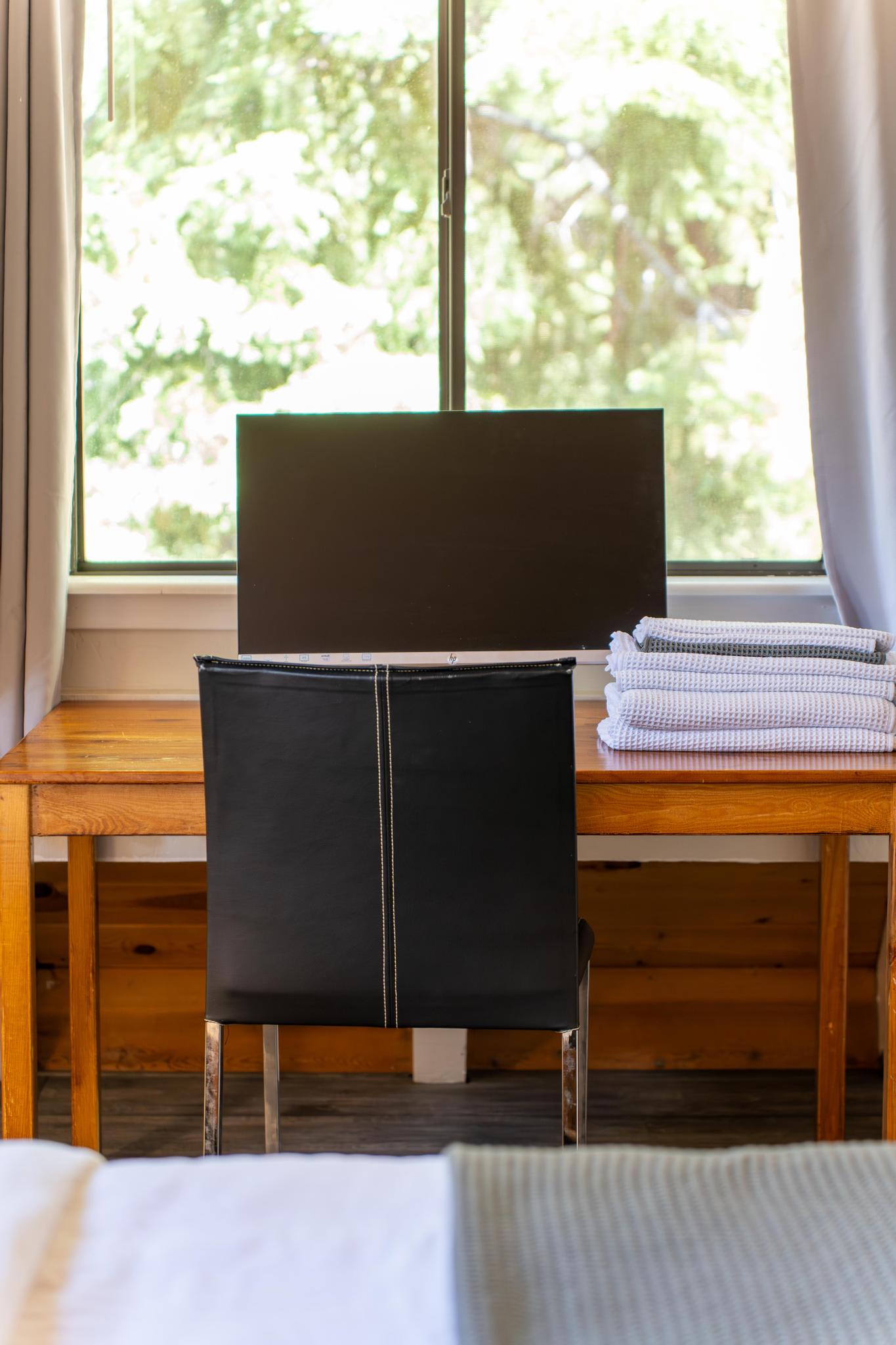 Work desk with a monitor, chair, and folded towels in a Tahoe Vista vacation rental, window view included.