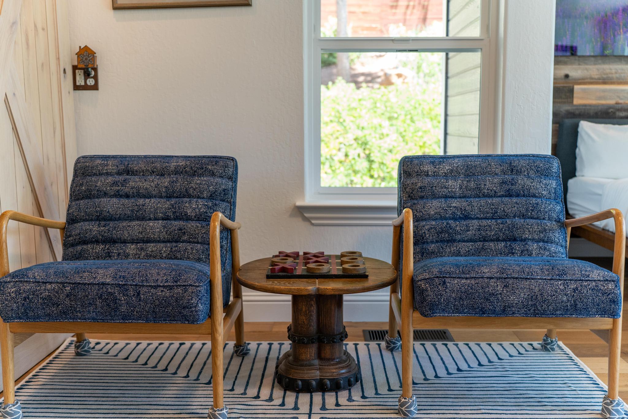 Two blue chairs and a wooden table with tic-tac-toe in a cozy Truckee vacation rental living room.