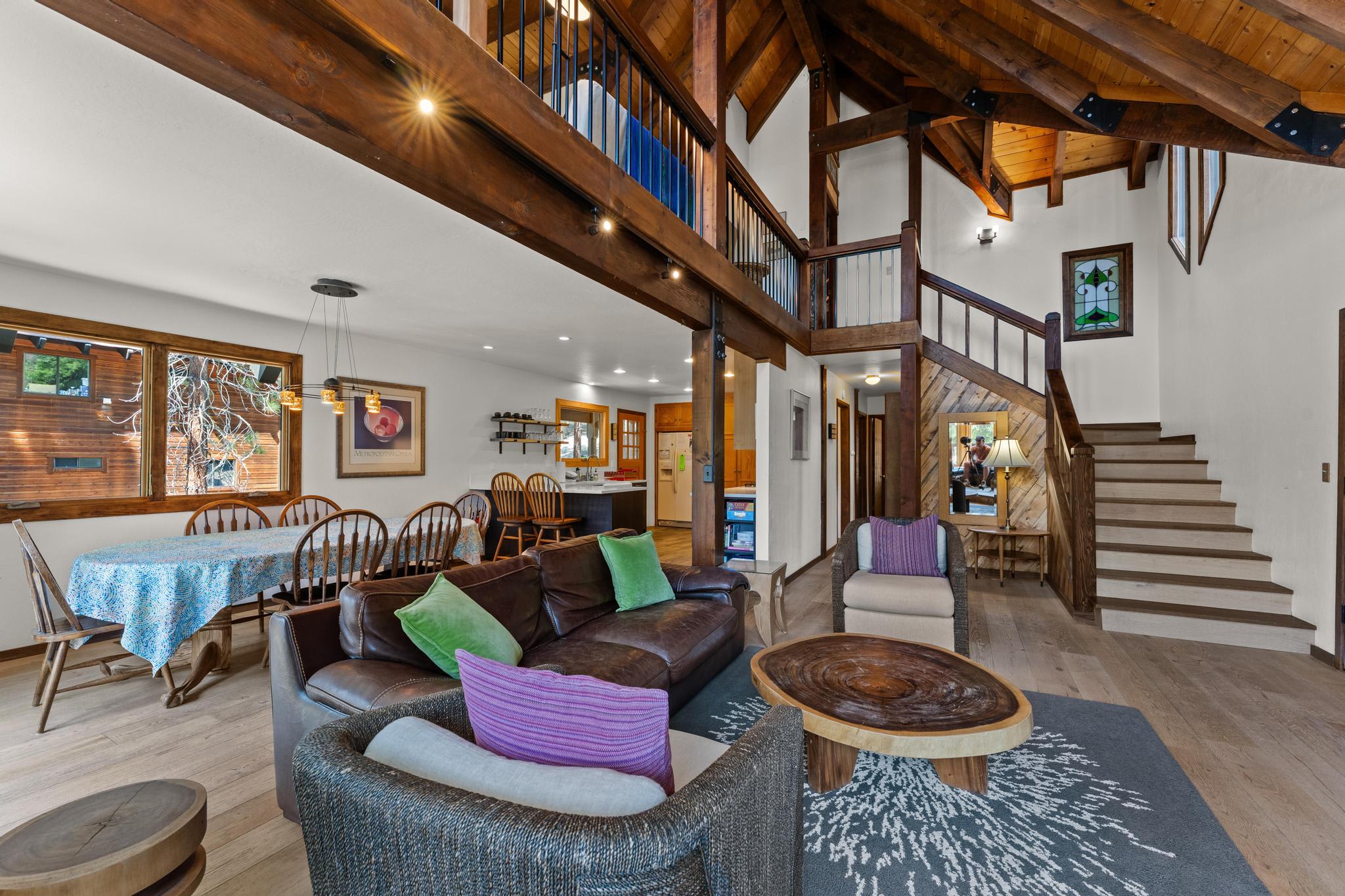 Spacious Tahoe Vista vacation rental with rustic wooden interiors, cozy seating, dining area, and stairs leading to a loft.