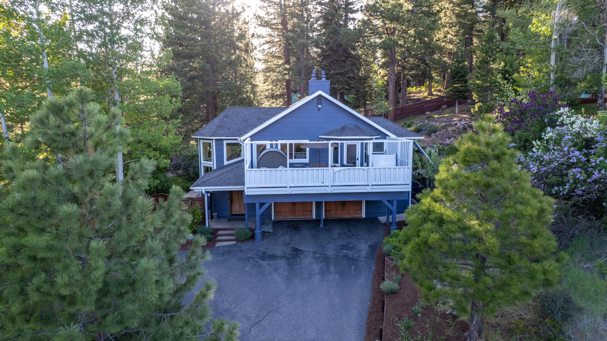 Charming blue vacation rental in Truckee, nestled among tall pine trees with a spacious balcony and serene surroundings.