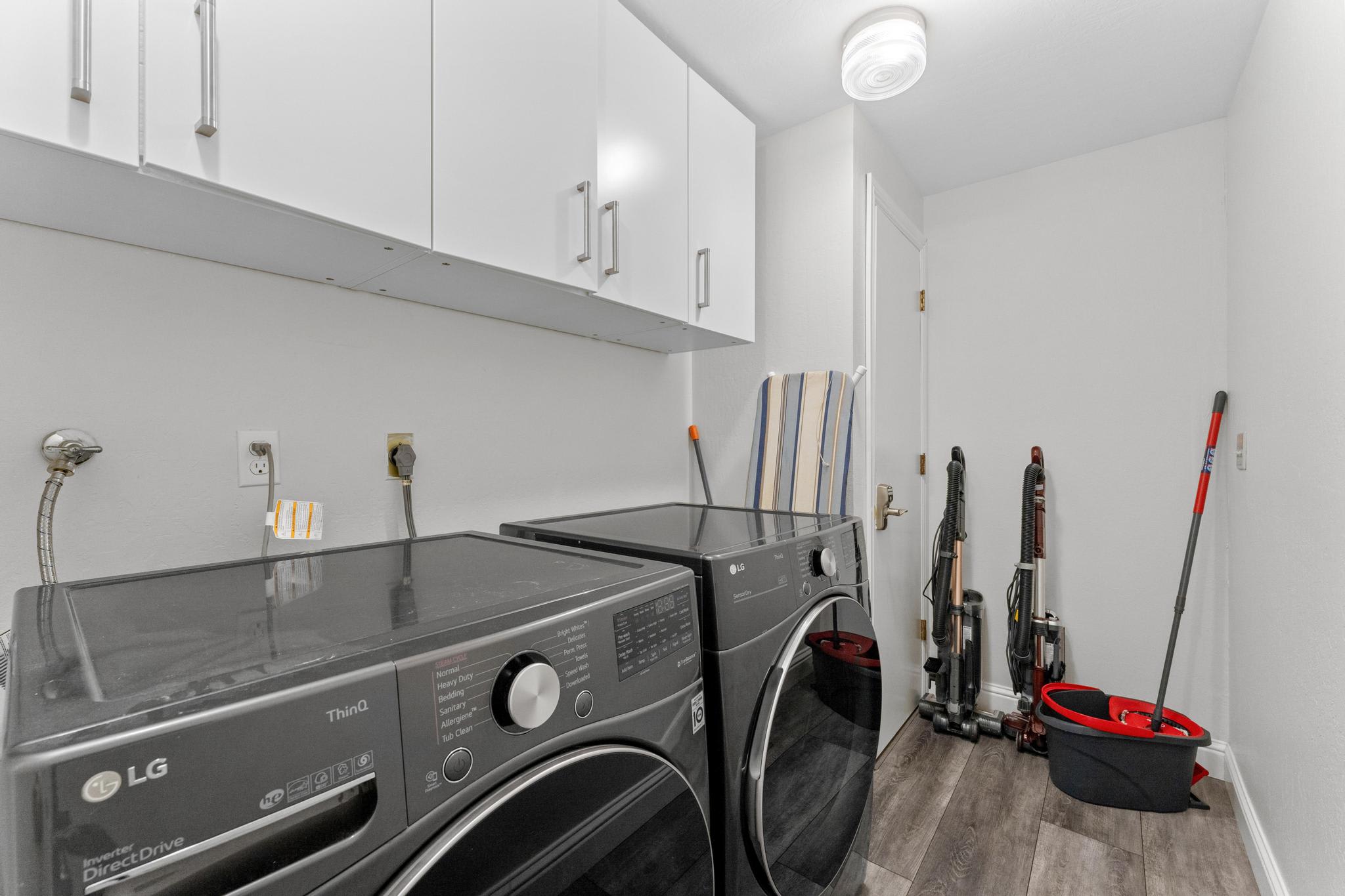 Laundry room in a Tahoe Vista vacation rental with washer, dryer, and cleaning tools neatly arranged.