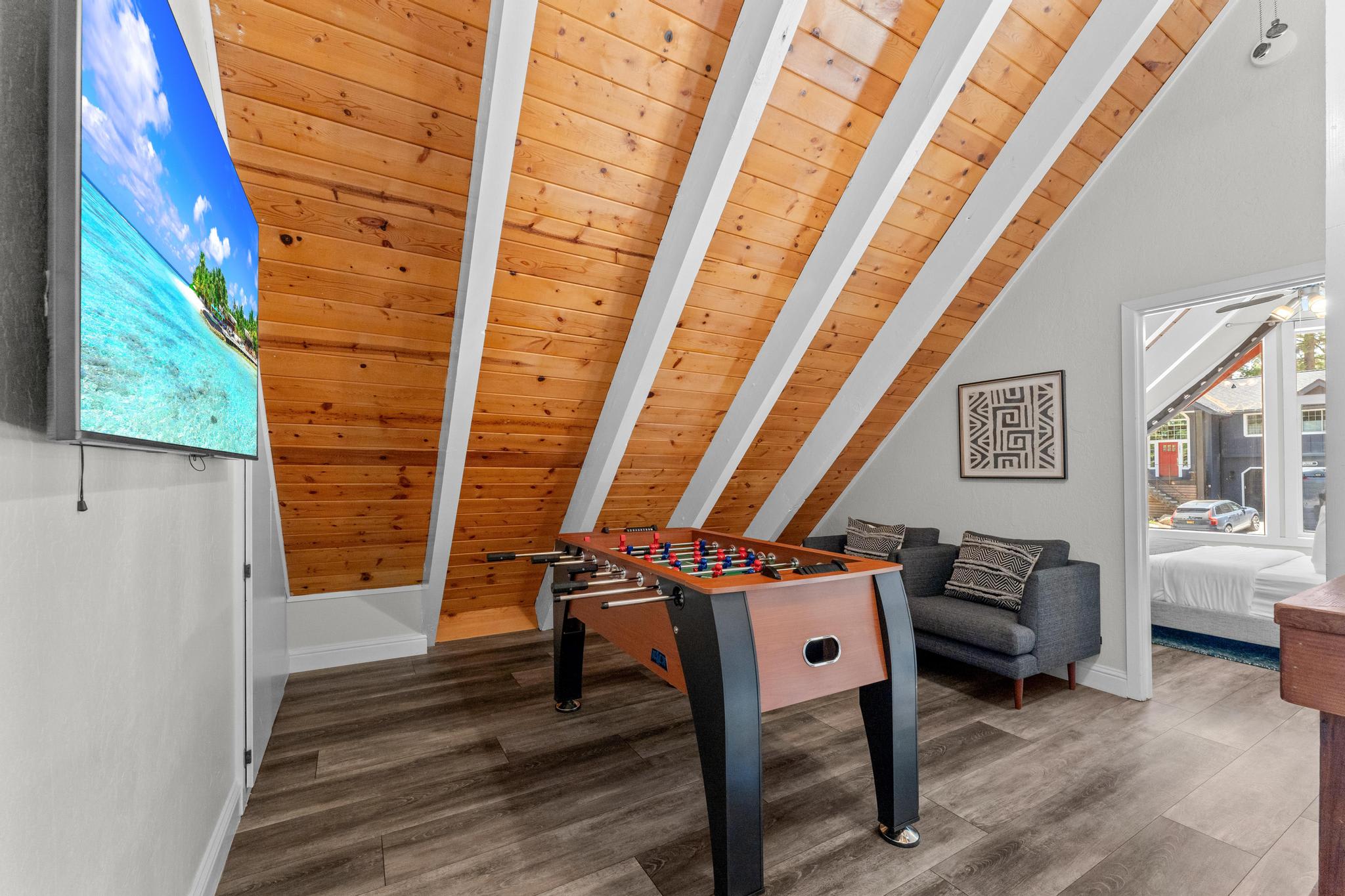 A cozy Tahoe Vista vacation rental with a foosball table, a modern couch, and a large window showing a scenic view.