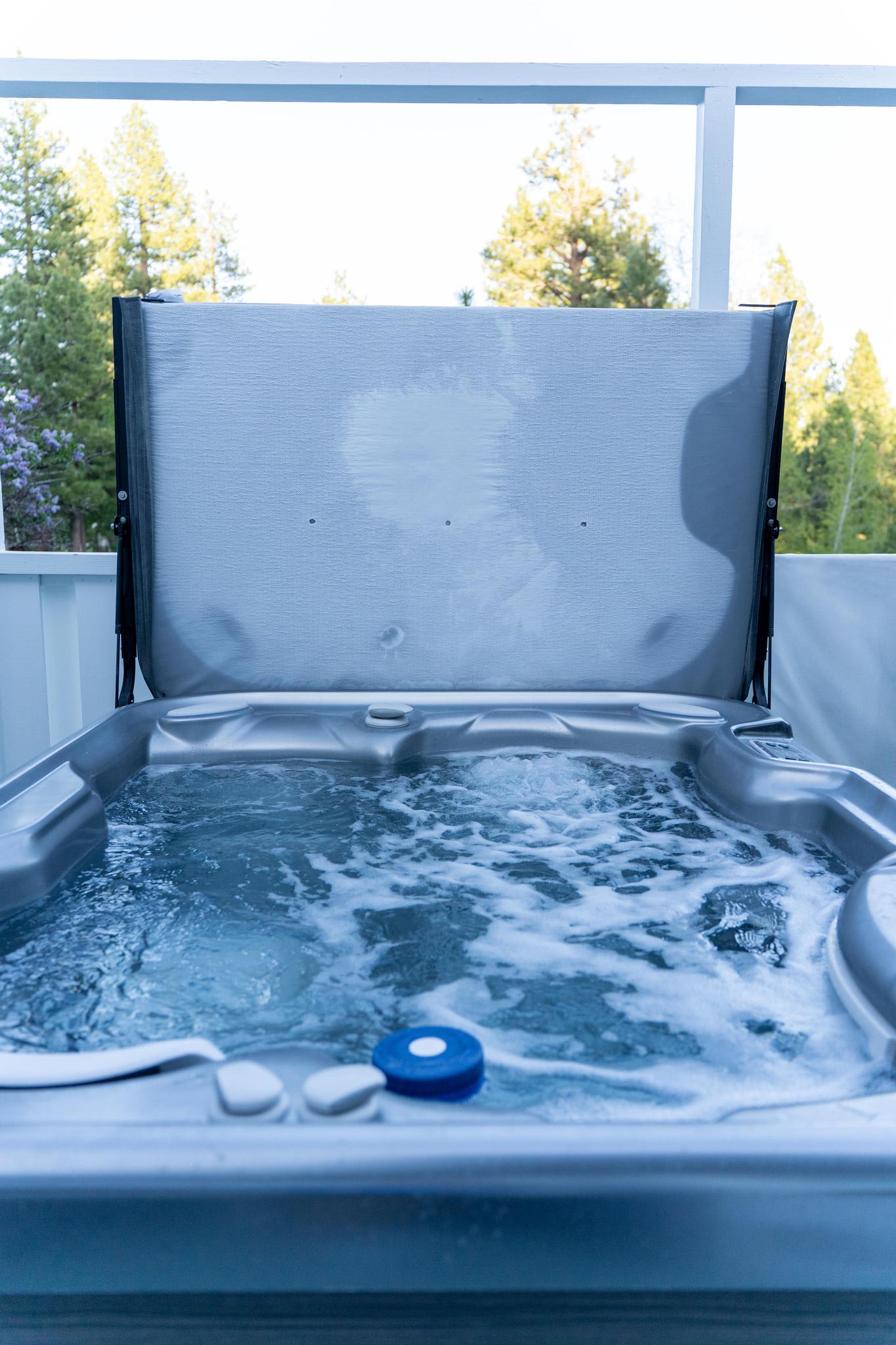 Hot tub on a deck overlooking trees at a Truckee vacation rental, perfect for relaxation and scenic views.