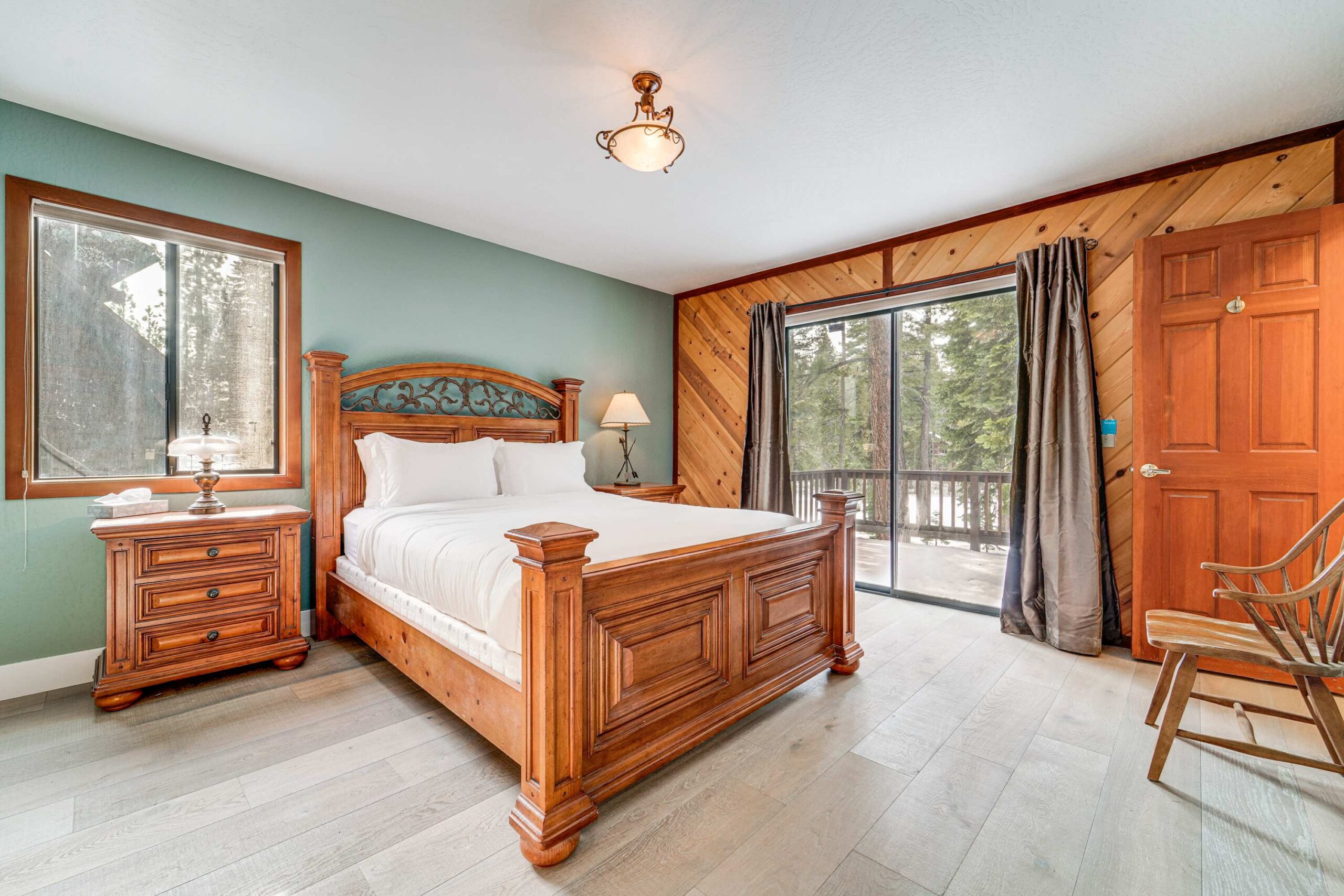 Bedroom in Truckee vacation rental with wooden furniture, a large bed, window, and forest view.