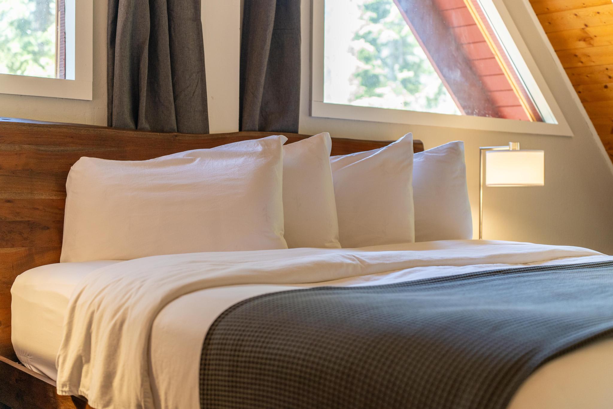 Cozy bedroom in a Tahoe Vista vacation rental with large windows, stylish decor, and plush bedding.